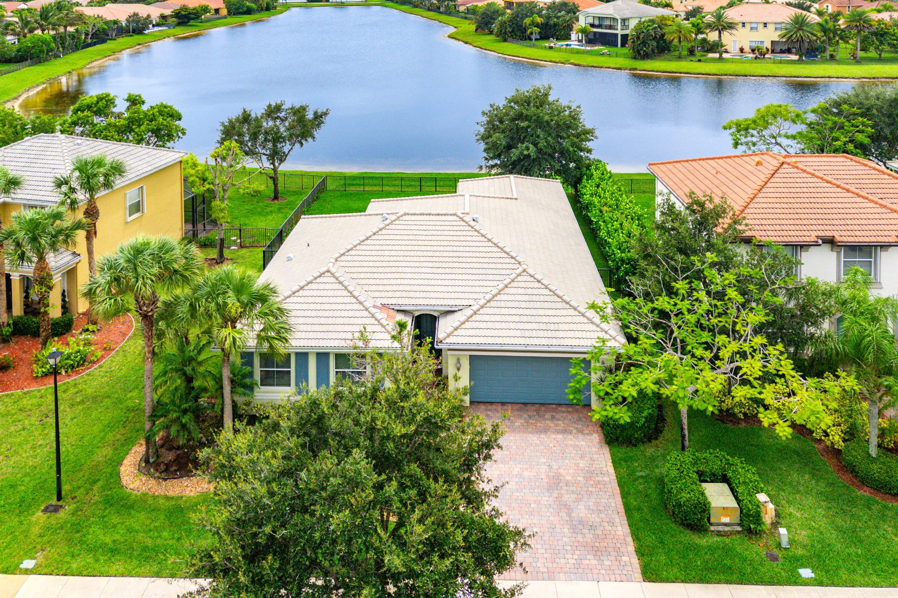 Welcome to The Cheerful House, a meticulously maintained single-story residence built in 2009 and perfectly positioned on one of Portosol's most desirable lakefront homesites. Offering a thoughtfully designed split floorplan with 3 bedrooms, a spacious office, and stunning long lake views, this home combines everyday comfort with elegant living. Step inside to discover an open and inviting layout featuring tile flooring throughout the main living areas and laminate flooring in all bedrooms and the office—completely carpet-free. The expansive living room showcases a beautiful tray ceiling, custom ceiling fans, and built-in speakers, while a wall of bright windows and sliding glass doors fills the space with natural light and frames the tranquil lake views.  This seamless connection to the screened patio creates an airy, open atmosphere that's perfect for both everyday living and entertaining. The well-appointed kitchen is designed to impress with granite countertops and backsplash, stainless-steel appliances, a double convection oven, glass cooktop, and a large walk-in pantry—everything a home chef could want. Retreat to the spacious primary suite featuring high ceilings, ceiling fan, two oversized walk-in closets with built-in shelving, and private access to the screened patio through sliding glass doors. The luxurious ensuite bath offers double vanities, a water closet, beautifully tiled walk-in shower with glass doors and a spa-inspired soaking tub framed by beautiful bright windows. Outdoor living is equally exceptional. Enjoy peaceful mornings and quiet sunsets from the covered and screened patio overlooking the long lake view. The fully fenced backyard offers privacy, manicured landscaping, a mature shade tree, rain gutters, and even a convenient doggy door for your four-legged family members.  Additional highlights include: • Dedicated laundry room with cabinetry & folding station  • 2-car garage  • Security system and surveillance cameras included  • Full hurricane protection with impact glass and panel shutters  • Recently cleaned roof and painted exterior  • Prime location near the rear community exit for added convenience  Resort-Style Living in Portosol Located within the highly sought-after Portosol gated community, residents enjoy an impressive array of amenities, including a clubhouse, fitness center, resort-style pool and spa, playground, basketball courts, tennis, pickleball, sidewalks, street lighting, and year-round community events. With two gated entrances and monitored visitor access, Portosol offers both security and an active lifestyle.  Conveniently situated just a short drive to Downtown CityPlace, the Kravis Center, beautiful beaches, parks, shopping, dining, and entertainment, this exceptional home offers the perfect blend of privacy, luxury, and location. The Cheerful House is more than a home—it's a lifestyle. Schedule your private showing today.