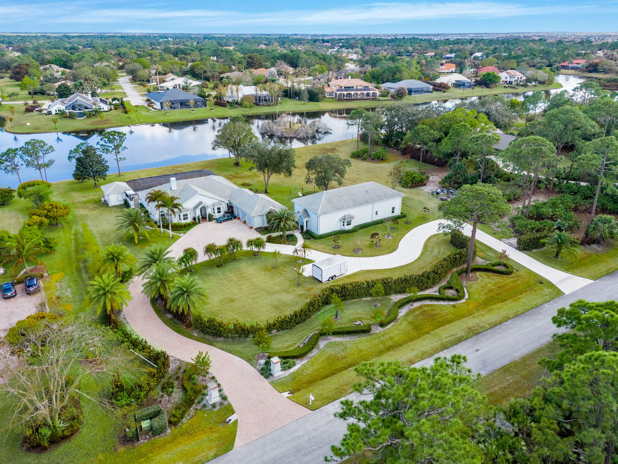 Custom Estate lakefront home in PGA Village. Experience refined estate living in the prestigious Sabal Creek at PGA Village. Situated on nearly 4 acres of private lakefront, this custom-built home offers exceptional space, privacy, and timeless design. The total home features approximately 6,000 square feet of living space with the main house featuring 3 BR's, 3.5 BA's, a large private office/den, a private 1-bedroom casita (4th BR), and expansive living areas ideal for entertaining. A well-appointed gourmet kitchen includes a gas range, abundant cabinetry, and generous counter space, opening seamlessly to the main living areas. Outdoor living is highlighted by a screened pool and covered lanai overlooking tranquil lake views, creating the perfect setting for relaxation and gatherings. The property also includes a separate two-bedroom, two-bath guest house with lake views, offering flexibility for guests or extended family, as well as an additional detached structure ideal for a private space.  Located within gated PGA Village, residents enjoy estate-sized lots, scenic surroundings, and proximity to championship golf, shopping, dining, and easy access to I-95 and the Florida Turnpike.  A rare opportunity to own a distinctive lakefront custom estate home in one of Port St. Lucie's most sought-after gated communities.