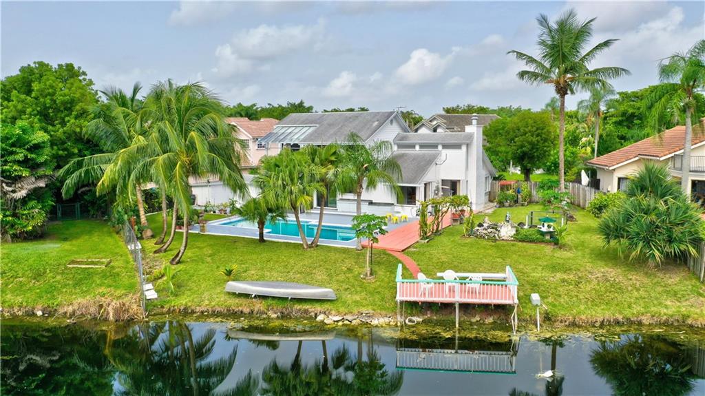 NOTE: Huge Adjustment to Sell this Weekend!  Elegant-custom pool-home, 85' Waterfront, Dock! Cul-de-sac in highly-desirable Jacaranda Country Club. Upgraded to perfection! SEE: Virtual Tour & Photos. Soaring volume ceilings, accordian shutters, fireplace, fenced yard, true outdoor kitchen, Roof in 2015, shed, lush landscaping, interior laundry area,   walk-in closets.  Floors: Upgraded engineered wood, tile & bamboo upstairs & stairs. Kitchen: Island, granite, upgraded cabinets. Energy efficient solar program. Near: Malls, shopping, banks, restaurants, houses of worship, much more. Easy access to FLL airport. One bedroom & bath located on first floor. 2nd story is Honey Board (50 year life expectancy). *NO HOA!*  Agent Must Accompany. NOTE:  A portable generator can accommodate hooking up the outdoor cooking area, as well as the AC in the Master Bedroom for emergencies.  The 2 small high windows are Impact Glass. Large Yard. Fruit trees are:  Papaya, Starfruit, Dragon fruit plus Coconut & Aloe plants.  Pond/water feature with pump. The outside main breaker panel has been replaced.  Washer/dryer are located in the garage, but there's a hookup in the inside laundry area.  Upgraded insulation. Crown molding. Family room with bar for entertaining. Kitchen has under-counter lighting.