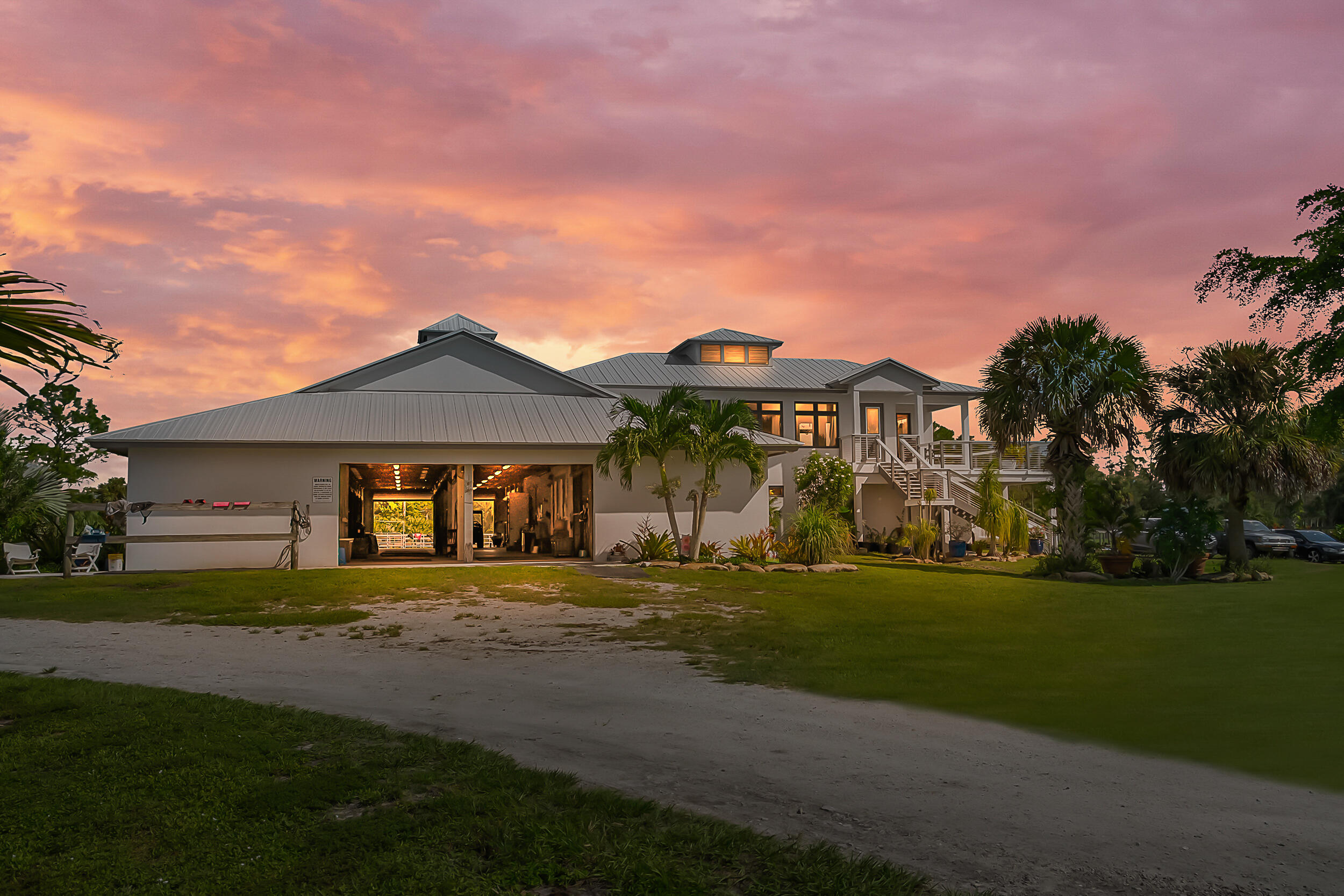 Positioned on 21.59 acres between Jupiter and Hobe Sound within the gated 41-parcel equestrian community of Trailside, this property offers a rare opportunity in an area where large acreage is increasingly limited. Trailside is known for its private, peaceful setting, spacious 20-30 acre parcels, and access to nearby riding and nature trails—all within a short drive to beaches, golf, and conveniences. Currently configured as a turnkey equestrian property, the property includes over 7,000 sqft of 2020-built CBS construction, featuring a well-equipped 13-stall center-aisle barn and two-story living quarters. A designated homesite with underground power allows for a future main residence, while existing improvements, including reverse osmosis to the home and paddocks, a generator, and quality infrastructure, support immediate use as a private retreat or working equestrian estate. The grounds are fully fenced and cross-fenced with multiple paddocks, a lit arena, round pen, and a mile-long riding trail. The surrounding area continues to see growth with new luxury golf courses and private club communities, while remaining nearby to Jupiter and Hobe Sound.