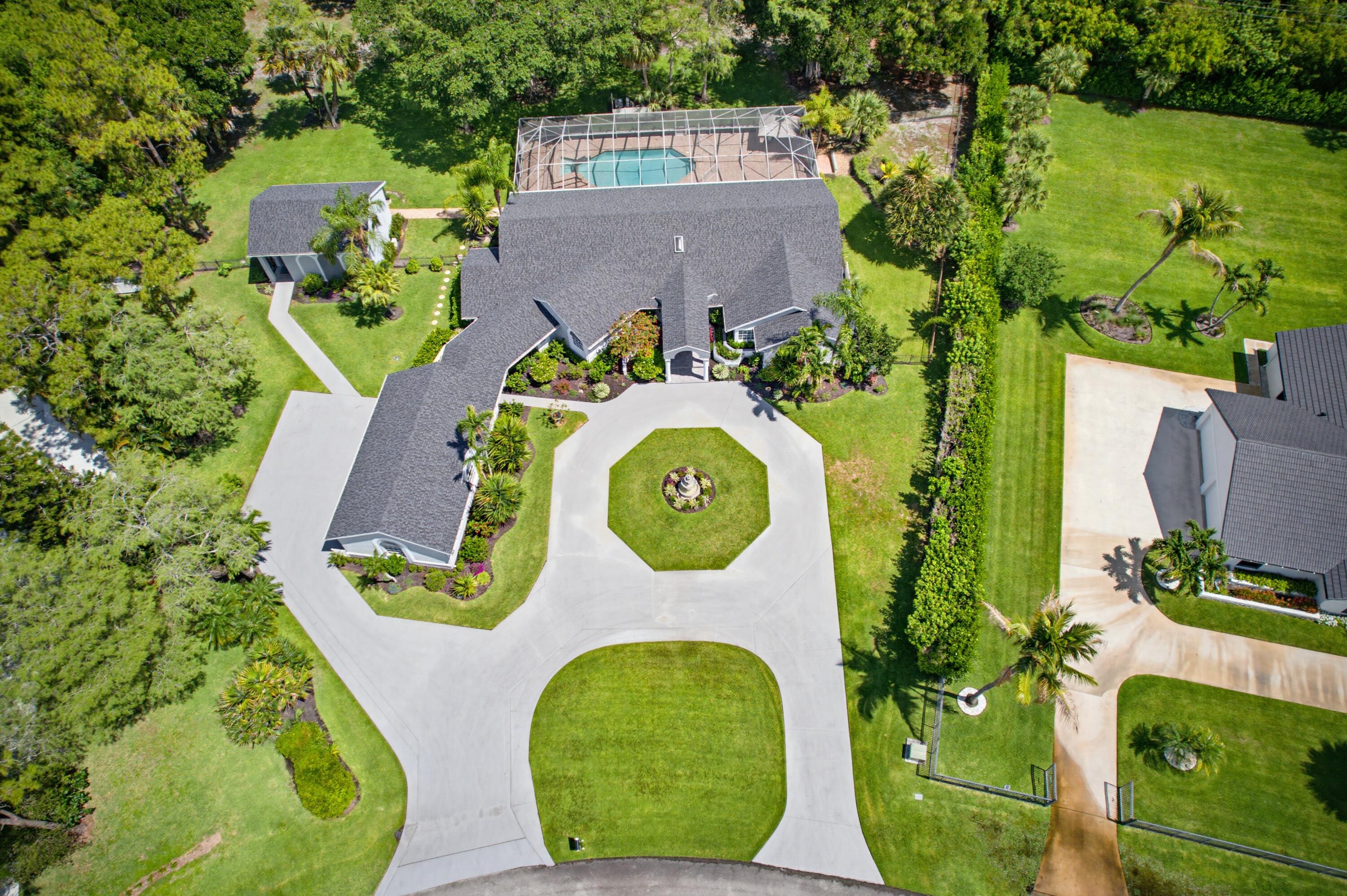 Tucked away on one of the largest and most private lots in highly sought-after Paddock Park, this extraordinary Wellington estate is more than just a home — it's a private resort-style compound designed for those who crave space, serenity, and endless possibilities. Situated on 3.33 lushly landscaped acres with NO HOA, this rare offering combines luxury, flexibility, and the ultimate South Florida lifestyle in one unforgettable property.   From the moment you arrive, the sprawling circular driveway, mature tropical landscaping, towering hedges, and estate-style presence create a sense of arrival rarely found in Wellington. Step inside the expansive single-story main residence where soaring ceilings, open-concept living spaces, and walls of glass invite natural light and picturesque backyard views into nearly every room.  The main home features 5 spacious bedrooms, 3.5 beautifully remodeled bathrooms, and a thoughtfully designed split floor plan ideal for both entertaining and everyday living. The oversized primary suite offers a peaceful retreat, while the secondary bedrooms provide exceptional flexibility for guests, offices, or fitness spaces. A detached 1-bedroom, 1-bath guest house creates endless opportunities for multigenerational living, seasonal guests, rental income, private office space, or live-in accommodations.  Outside is where this property truly becomes unforgettable. The massive fenced backyard feels like your own private park, complete with a resort-style screened pool and spa, sprawling patios, mature exotic trees, paver walkways, and endless green space. Whether you envision adding a tennis court, pickleball court, basketball court, equestrian amenities, or simply enjoying the privacy and open space, this property delivers a lifestyle few homes can offer.  Extensively updated with a new roof (2024), new screen enclosure (2024), fresh interior and exterior paint (2025), remodeled bathrooms, updated flooring, doors, hardware, and more, the home blends modern improvements with the opportunity to customize the kitchen space to your exact vision. Additional highlights include a 4-car air-conditioned garage, whole-house reverse osmosis water system, 22KW Generac propane generator, separate guest house access, multiple driveways for boats, trailers, or recreational vehicles, and over half an acre of untouched land further enhancing the estate's privacy.    Located in the heart of Wellington near world-renowned equestrian venues, top-rated schools, fine dining, shopping, parks, and only minutes to major highways and Palm Beach International Airport, this one-of-a-kind property offers the rare combination of acreage, privacy, location, and freedom that today's luxury buyers are searching for.    This is not just a home — it's the opportunity to create the Wellington estate lifestyle you've always imagined.