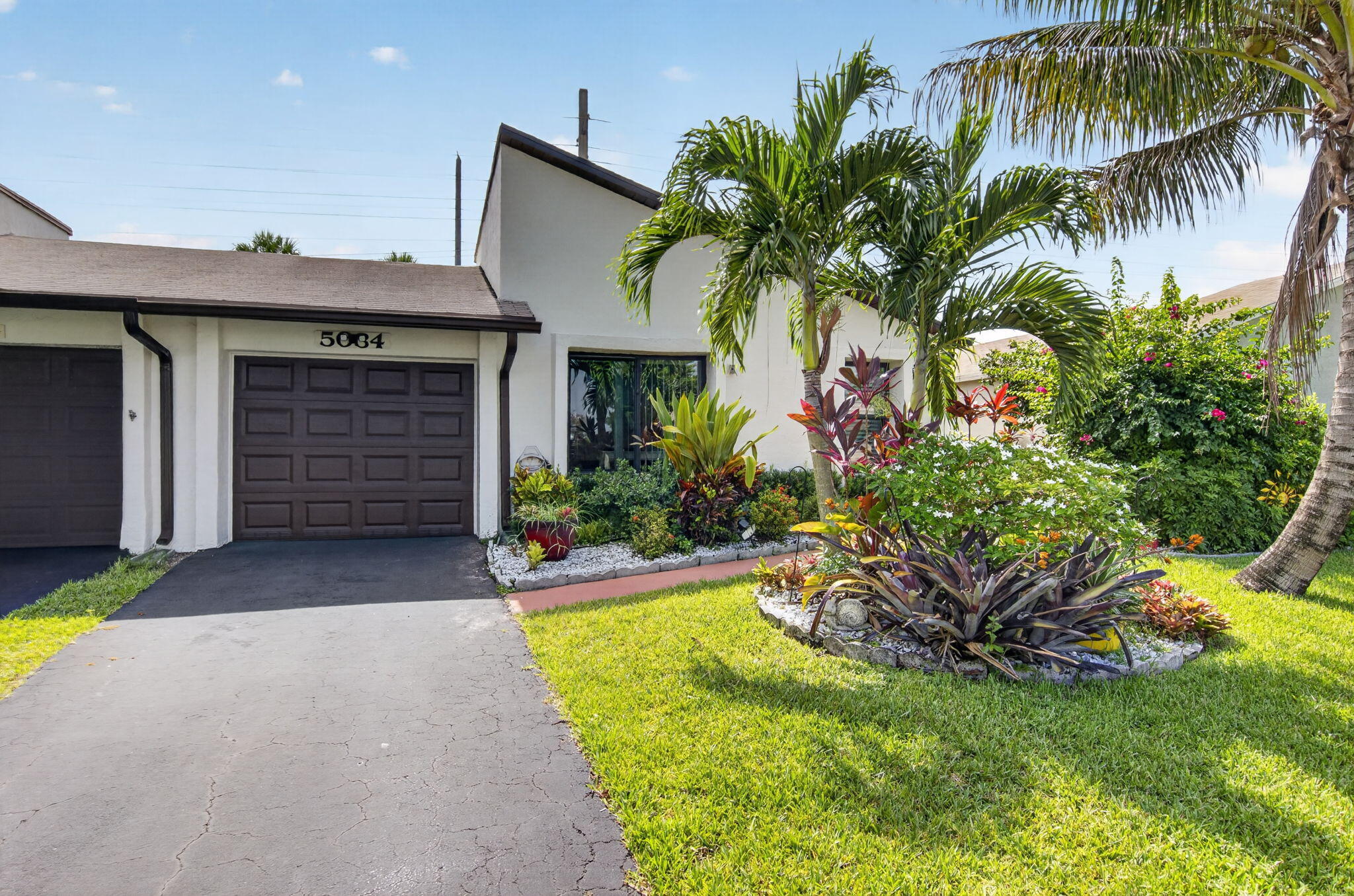 Welcome HOME to this beautifully maintained 2BR/2BA villa in the cozy Mirror Lakes community.  This inviting, open-concept home features a new hurricane-impact front door, impact windows throughout, newer W/D, updated kitchen lighting, screened porch enclosure, custom closet organization, and convenient attic storage.  The garage features a finished floor and is currently under air, offering flexible space for a workshop, home gym, or hobby area.  The spacious living area is enhanced by an enclosed sunroom overlooking the private backyard patio.  Meticulously cared for and move-in ready, this villa offers comfort, functionality, and plenty of space to enjoy FL living.  Select furnishings are negotiable, making your transition even easier!