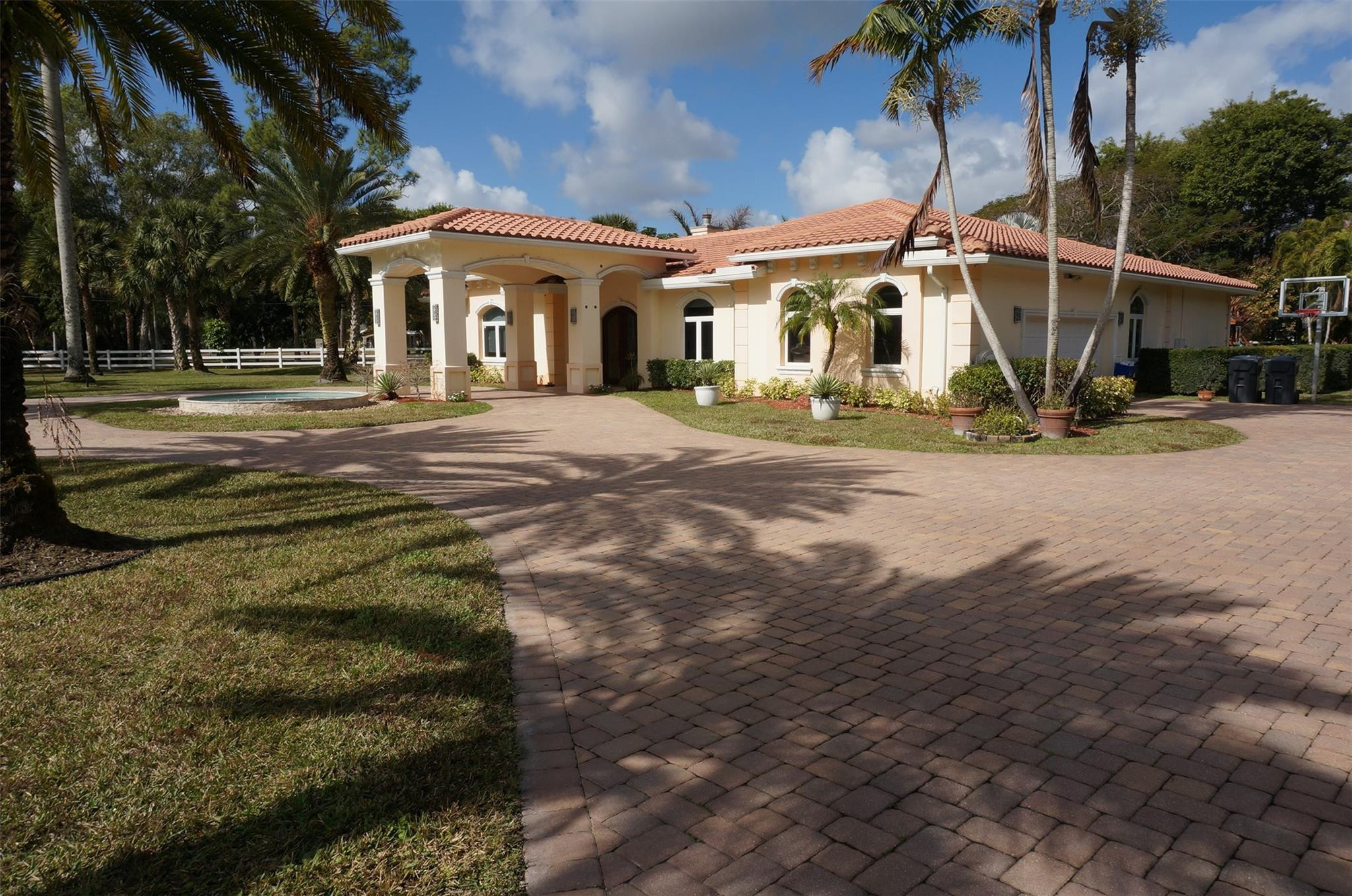 Exceptional luxury estate on 2.04 fenced acres featuring 3 spacious suites, private office, and upscale finishes throughout. Highlights include 12-ft ceilings, marble floors, Swarovski chandeliers, impact windows/doors, motorized blackout blinds, and oversized primary suite with dual XL walk-in closets. Gourmet kitchen boasts KitchenAid stainless appliances, farm sink, and granite counters. Resort-style outdoor living includes a heated 20x40 saltwater pool with spa and swim jets, infrared sauna, and covered patio with motorized screens. Barn with 2 horse stalls, motorized gates, circular driveway, paid-off solar, Tesla charger, 2 newer A/Cs, 2 tankless water heaters, dual wells with Kinetico system, garage storage, and mature avocado tree complete this rare private retreat. Luxury 3-suite estate on 2.04 acres with high-end finishes throughout. Features include an oversized master with two XL walk-in closets, office, 12 ft ceilings, marble floors, impact windows, motorized blackout blinds, and custom wooden impact doors. Gourmet kitchen with stainless KitchenAid appliances, farm sink, and granite counters. Outdoor oasis offers a 20x40 heated saltwater pool with spa and swim jet, infrared sauna, covered patio with motorized screens. Home includes paid-off solar, Tesla charger, 2 newer A/Cs, 2 tankless heaters, 2 wells with Kinetico system, barn with 2 stalls, fenced motorized gate, circular driveway, and avocado tree. Welcome to this exceptional luxury estate situated on 2.04 acres in a highly desirable corner lot location. Designed with elegance, privacy, and comfort in mind, this property offers an impressive blend of high-end finishes and modern conveniences. Featuring 3 spacious suites, an oversized master bedroom with two extra-large walk-in closets, and a private office, this home is perfect for those seeking space and sophistication.Step inside through the custom-made wooden impact front door and immediately appreciate the high 12 ft ceilings, marble floors, Swarovski chandeliers, and custom high wooden doors throughout. The home is equipped with impact windows, motorized blackout blinds, and a wooden fireplace, adding both style and functionality.The gourmet kitchen features stainless steel KitchenAid appliances, a farm-style sink, granite countertops, and ample space for cooking and entertaining. Two tankless water heaters, two newer A/C units, a paid-off solar system, and a Tesla charger add tremendous energy efficiency and peace of mind.Enjoy resort-style outdoor living with a massive 20x40 saltwater heated pool, complete with jets for lap swimming and a spa. Relax in the infrared sauna, or unwind on the covered patio with motorized screens. The fully fenced property includes a motorized front gate with keypad, a second rear gate for barn access, and a circular driveway with a covered entrance.Ideal for equestrian or hobby use, the property includes a barn with two horse stalls, additional storage, and space for a manure bin. The home offers two wells—one dedicated to full-property irrigation and the other supplying the residence with a Kinetico water softener system, plus an additional under-sink softener for kitchen use. An avocado tree adds a touch of nature and homestead charm.Additional features include:• Built-in overhead garage shelving• Custom craftsmanship throughout• Spacious grounds with endless potentialA true rare find—this estate combines luxury, privacy, and practicality in one spectacular package. Don't miss this opportunity to own a masterpiece.