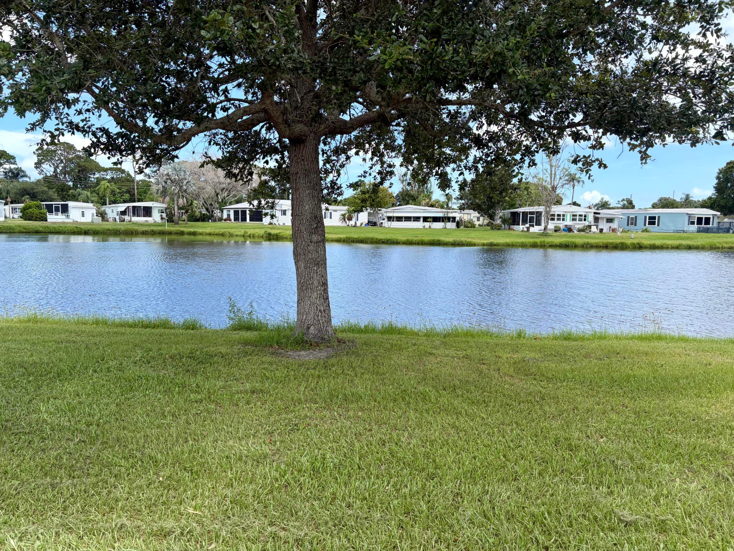 Are you someone who loves living on the water? Well then, we are offering an opportunity to live on The Saint Lucie River with views galore and views from the front of the home are of a private lake as well. Enjoy all the 55+community has to offer with tennis, golf, pickle ball, social activities, pool, all maintained for you with lawn care, trash and recycle and lots of great clubs to enjoy! Close to shopping, medical, entertainment, marinas, farmers market, botanical gardens, and great Florida fishing. There is a boat launch right in the community! This home offered mostly furnished as shown with the exception of a few prize art pieces and some personal items and of course they are keeping their comfy king bed and 1 TV. Making this a great place for entertaining and just plain enjoying  the Florida lifestyle.  Kitchen affords lots of storage cabinets and primo granite countertops for a fresh clean crisp look and durability. No worries on this home maintenance with a new CENTRAL air unit just 3 months old and shingled roof is just 7 years.  Floors are freshly carpeted and both baths are newly updated. Of course, it's always nice to have a den to get away and relax but to have the river view from the den is MAGIC! Impact windows offer security and 20x15 screened room is an excellent way to spend your evenings watching the everchanging sunsets from the privacy of your own back yard surrounded by nature and tropical vegetation. Carefully selected landscaping adds to the charm and privacy that avails the lifestyle you deserve. ON LEASED LAND YOU WON"T PAY PROPERTY TAX HERE! If you've been wanting to make the move this is an opportunity, you'll need to explore, so give me a call today for updates and private showings.