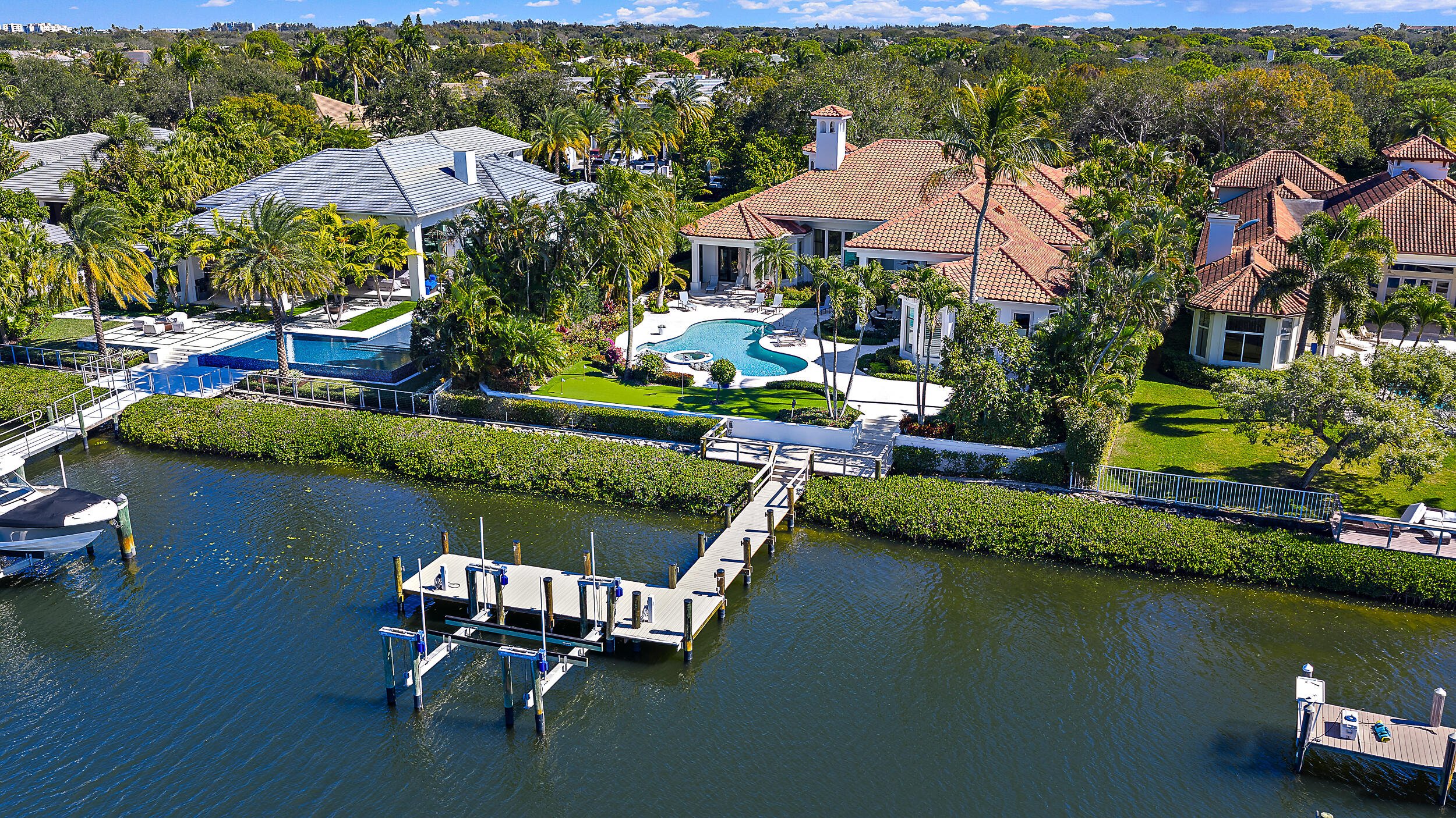 Located in the prestigious waterfront community of Admirals Cove, this beautifully renovated single-story estate offers approximately 7,000 square feet of living space on an oversized lot with a substantial driveway, expansive backyard, and a full golf membership! With approximately 100 feet of waterfrontage, bring your large boats and move right in to enjoy the amazing Admirals Cove lifestyle with no fixed bridges and direct ocean access. Inside, the home features high ceilings and abundant natural light throughout. The kitchen is a standout, with large windows that fill the space with natural light and overlook the outdoor areas and water. Just off the kitchen is a well-appointed bar, creating a natural gathering space for entertaining.  The outdoor areas feature a pool, spa, and putting green overlooking the water, along with an outdoor kitchen complete with grill, wet bar, and mini refrigerator. The primary suite is generously sized and includes a spa-like wet room bath, offering a clean, modern design. Residents of Admirals Cove enjoy access to an exceptional collection of amenities, including a full-service marina, 45 holes of championship golf, two clubhouses, two driving ranges, tennis and pickleball facilities, a state-of-the-art fitness center, luxury spa, and multiple waterfront dining venues. The club also offers an active social calendar and world-class service, making Admirals Cove one of the most sought-after private club communities in South Florida.