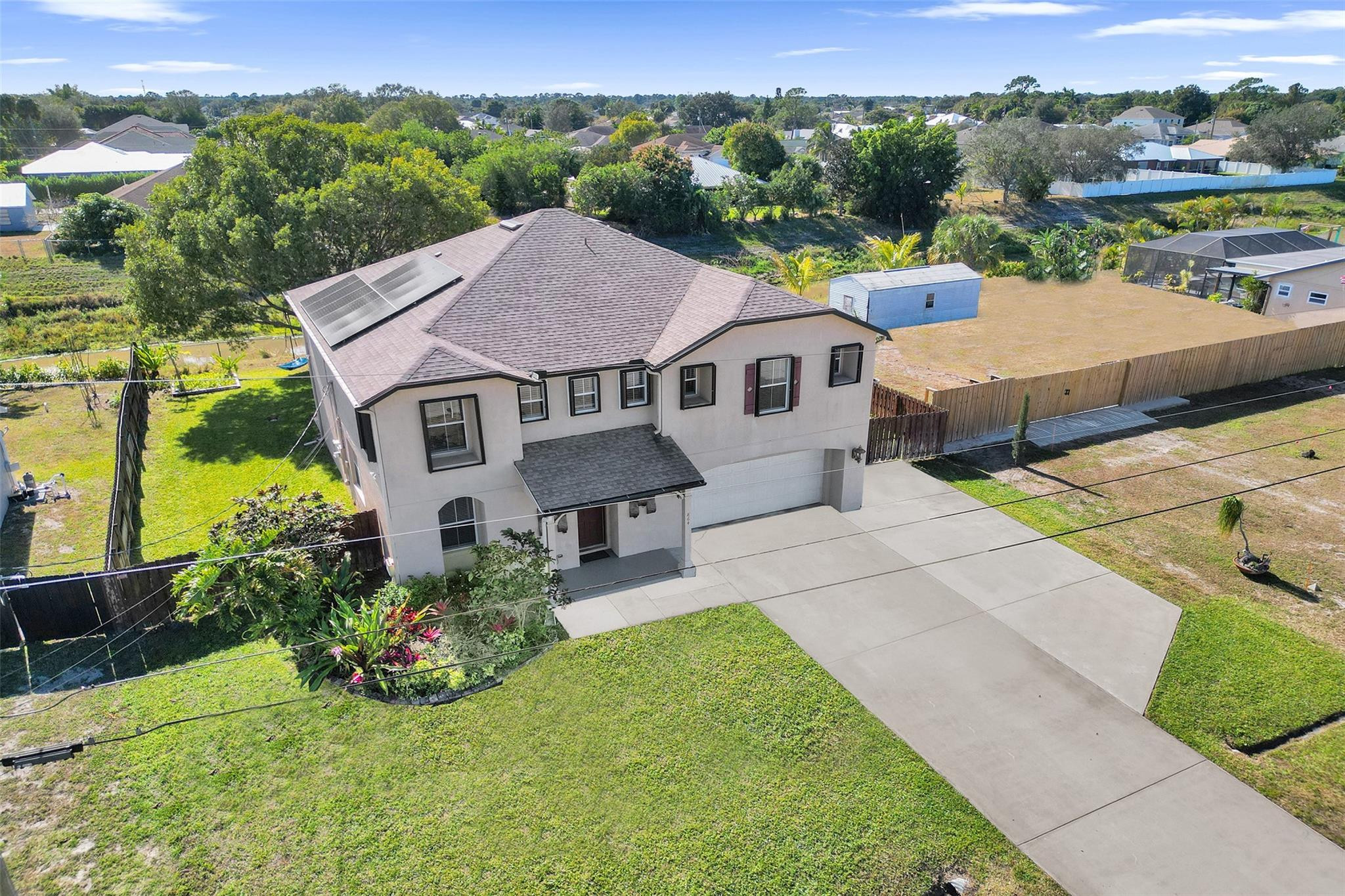 NO HOA!! Excellent value for this spacious 3,057 sq ft two-story home designed for comfortable family living and entertaining. NEW ROOF (2023), PAID-OFF SOLAR PANELS, HURRICANE PROTECTION, WIRED CAMERA SYSTEM, AND GENERATOR HOOKUP—maximum efficiency, security, and peace of mind. This 4-bedroom, 3-bath layout features oversized bedrooms with walk-in closets, 2 LARGE FAMILY ROOMS, and a main-level guest suite. The open kitchen flows to a large covered patio overlooking the fenced yard and canal. Efficient well-water sprinkler system. 10,000 sq ft lot with an extra-large EXTENDED DRIVEWAY for your RV, boat, or golf cart parking, a two-car garage with storage, separate storage shed. VERY low cost power bill. Room for a pool. New lake nearby. It's a PERFECT home for your family and pets!