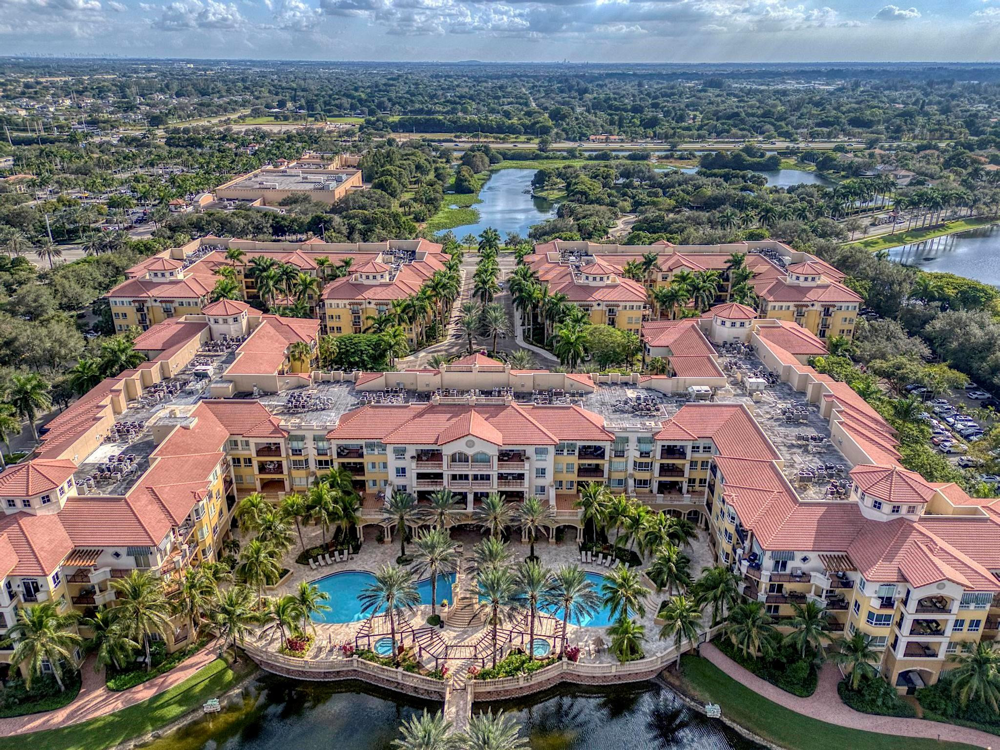 Welcome to this first-floor corner residence in the main bldg of the guard-gated 55+ community of The Palms Weston. Featuring 13+ High Ceilings with prime location near all activities/ amenities, this 2-bed, 2.5-bath condo has garden views and Large Balcony with a convenient private Patio Entrance that offers direct access to the grass area for easy pet walking. The kitchen has wood cabinetry & stainless-steel appliances. The open layout includes crown molding, laminate/tile floors throughout, 6-Yr Warranty on All Appliances + AC, Independent Storage Unit and 3-Main Entrance Ways. Primary suite offers a walk-in closet, dual vanities, and separate shower. Enjoy resort-style amenities & the convenience of an on-site Cleveland Clinic, plus proximity to Hospital, major hwys, Publix, & dining.
