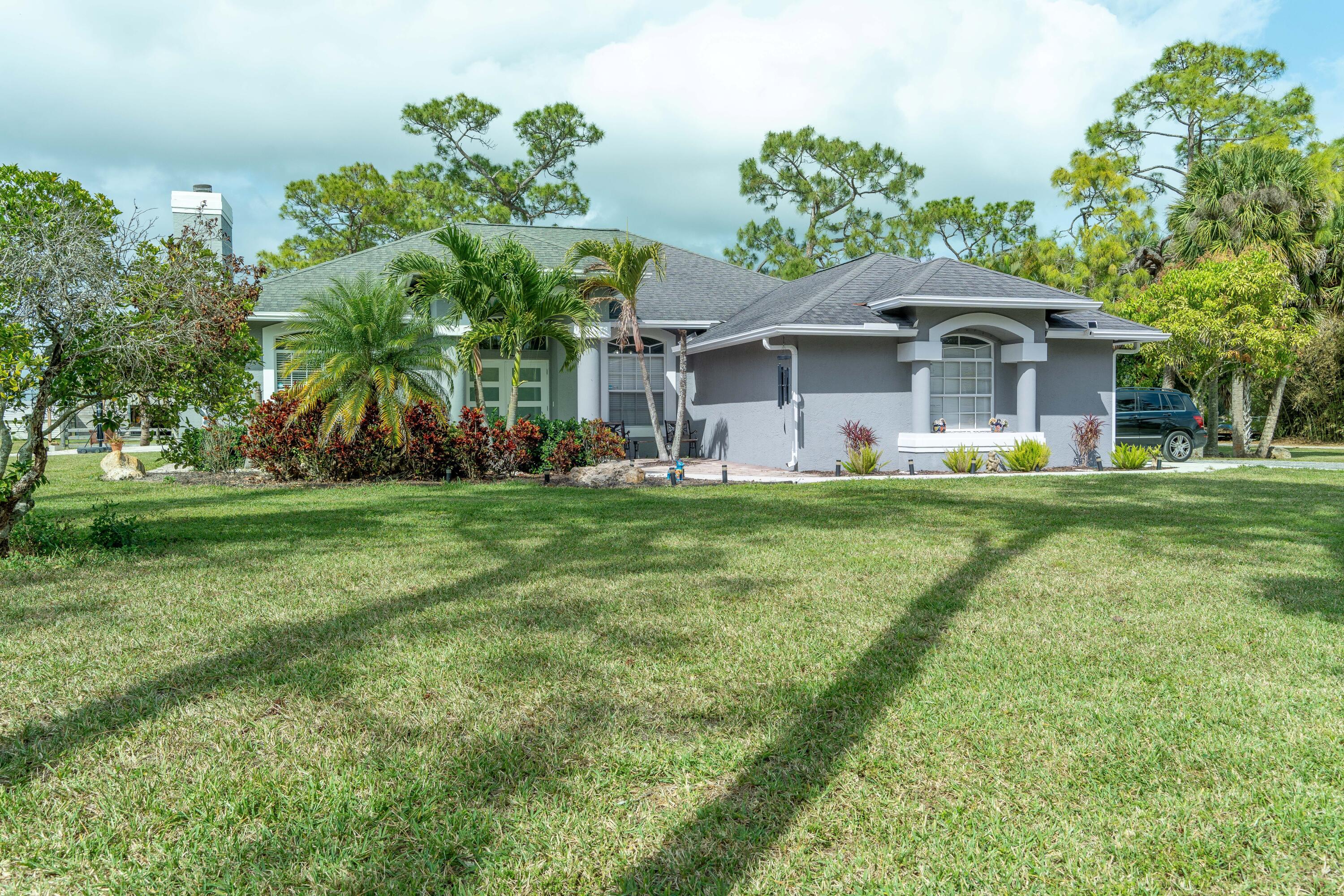 Welcome to this single-story residence in Loxahatchee Groves, nestled on five lush acres, this single-family residence combines country charm with practical agricultural potential. This four-bedroom, three-full bath home provides functional layout, plus family room, home office, private pool. Situated in the Loxahatchee Groves community, this property presents a practical option for those seeking private / Equestrian residential living in the area. bring your horses to a 9-stall barn with tack room, plenty of space to park your trailers. fully fenced, perfect for seeking space, privacy and a country feel.