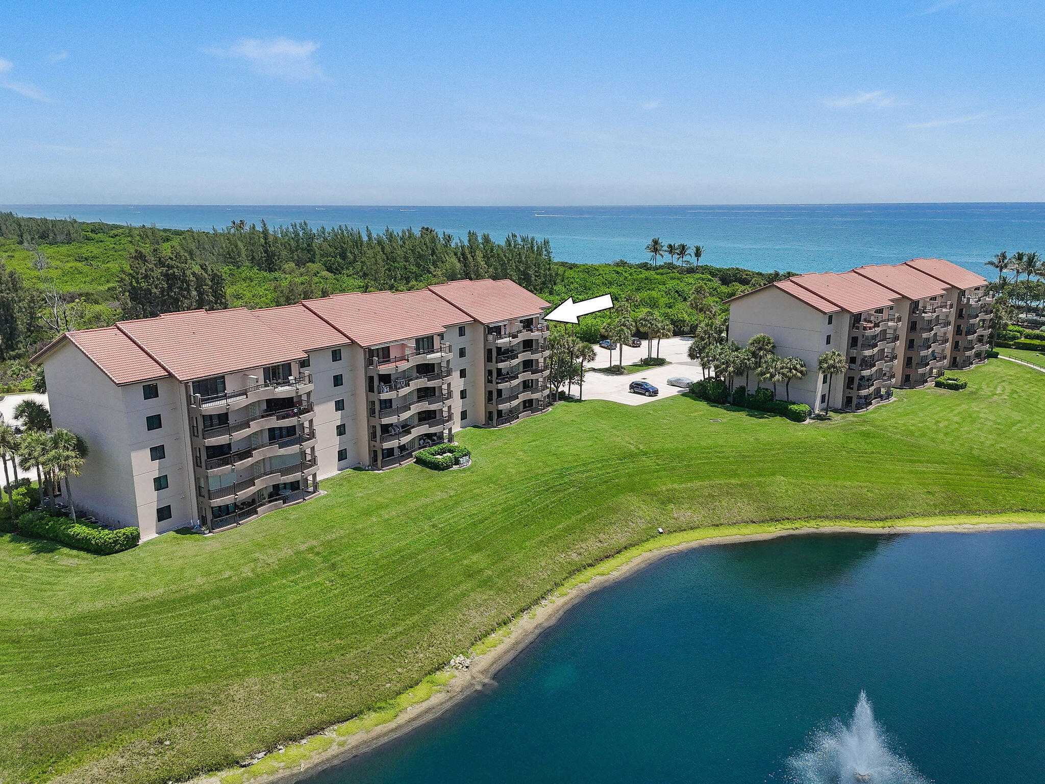 Perched on the penthouse level, this beautifully updated residence offers soaring vaulted ceilings, abundant natural light, and sweeping views of the Atlantic Ocean, tranquil lake, and protected natural preserve. Ideally positioned just steps from Jupiter's pristine beaches, this spacious two-bedroom, two-bath condominium captures the essence of effortless coastal living. The thoughtfully designed split floor plan features an expansive great room with dramatic vaulted ceilings, luxury wood-look flooring, and sliding glass doors that open to a private covered balcony complete with an electric retractable awning—the perfect setting to enjoy ocean breezes, spectacular sunrises, and picturesque water views. The renovated open-concept kitchen is appointed with quartz countertops, custom cabinetry, stainless steel appliances, and a breakfast bar that seamlessly connects to the dining and living areas, creating an ideal space for everyday living and entertaining.  The spacious primary suite enjoys beautiful ocean and lake views, a custom walk-in closet, and a stunning renovated ensuite bath with a frameless glass shower and designer finishes. A generously sized guest bedroom and beautifully updated guest bath provide comfort and privacy for family and visitors, while the versatile room is ideal as a home office, fitness room, hobby space, or additional storage.  Additional highlights include hurricane-impact windows and sliding glass doors, an impact-rated front door, full-size laundry room with side-by-side washer and dryer, and ample storage throughout.  Residents of Ocean at the Bluffs South enjoy 24-hour gated security, a resort-style pool, tennis courts, on-site management, beautifully maintained grounds, and private beach access. Conveniently located near Jupiter's renowned beaches, Juno Pier, waterfront dining, shopping, golf, and entertainment, this exceptional penthouse offers the ultimate South Florida lifestyle.