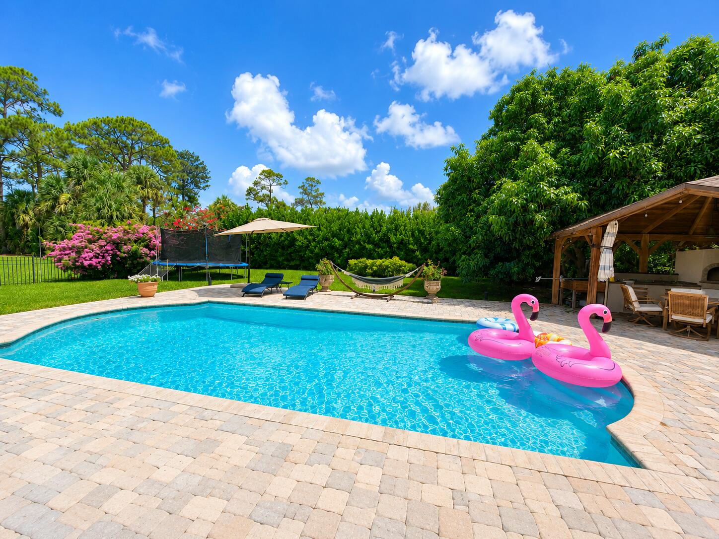 Discover a rare opportunity in Pinewood of Wellington, offering over an acre of privacy with no HOA. This spacious 4-bedroom, 3-bath home plus a dedicated office features a desirable split-bedroom floor plan, vaulted ceilings, and generous indoor-outdoor living spaces. The private backyard is designed for Florida living with a large in-ground pool, spa, sauna, covered patio, outdoor kitchen, and detached gazebo with a built-in pizza oven and grill. Mature tropical landscaping and fruit trees, create a private backyard oasis. A circular driveway welcomes you home, while the 2-car garage and Tesla charging add everyday convenience. Conveniently located near Wellington shopping, dining, equestrian venues, major roadways, and highly rated local schols.