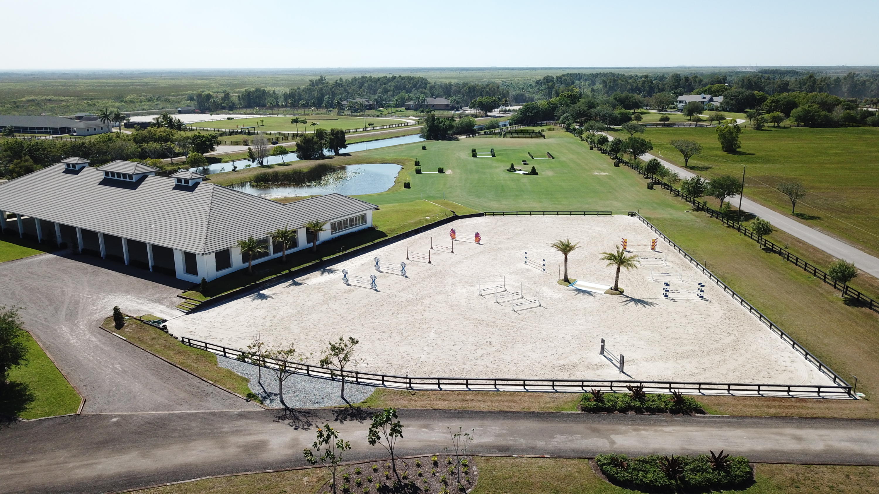 Palm Beach Point on one of the largest contiguous tracts available (3 Lots). An incomparable professional facility completed in 2016 on over 16 acres. 20 stall center aisle barn has 8 grooming & wash stalls, 2 tackrooms, hot and cold water wash stalls, extended laundry room with double set of machines and extensive storage space, oversized feed room, and 2 staff apartments. Three arenas including covered, outdoor and derby field. Exquisite estate home, fully renovated in 2016 offering captivating views of the expansive property floods the interior with natural light from it's floor to ceiling windows. Snaidero kitchen design, indoor and outdoor Porcelanosa  Urbatex tile, private master retreat and additional 5 bedrooms with en suite bathrooms.
