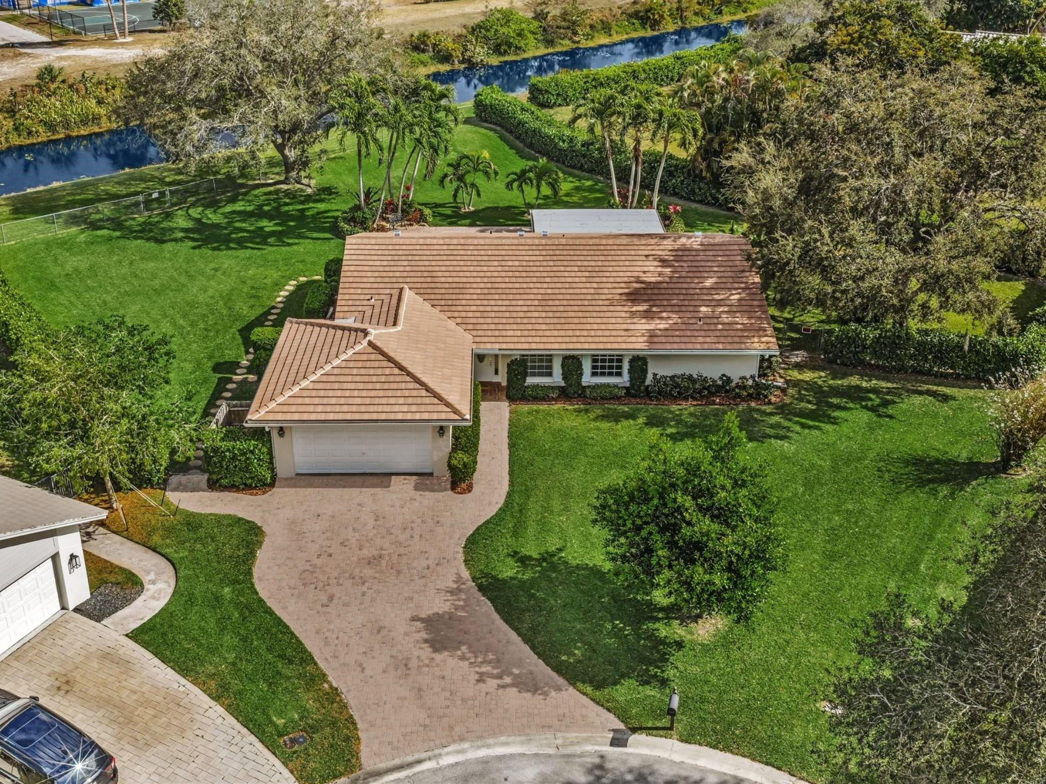 RARE OPPORTUNITY! One-story waterfront pool home on an oversized 17,292 SF fenced lot located on a quiet cul-de-sac in the heart of Coral Springs. NEW ROOF (2025) with warranty and new gutters. Paver driveway,  walkway, & patio. Freshly painted interior and exterior. Hurricane Shutters.This home offers a flexible layout with a spacious great room, dining area, and living room. Split bedroom plan provides privacy. Updated primary bathroom. Additional upgrades include a new hot water heater, new washer and dryer, French doors, & crown molding.The kitchen features tall cabinets, an open pass-through, and extra refrigerator in the garage. Open pool was resurfaced with Diamond Brite (2025), creating an ideal outdoor space for entertaining, play, or future expansion. Generator ready! NO HOA.