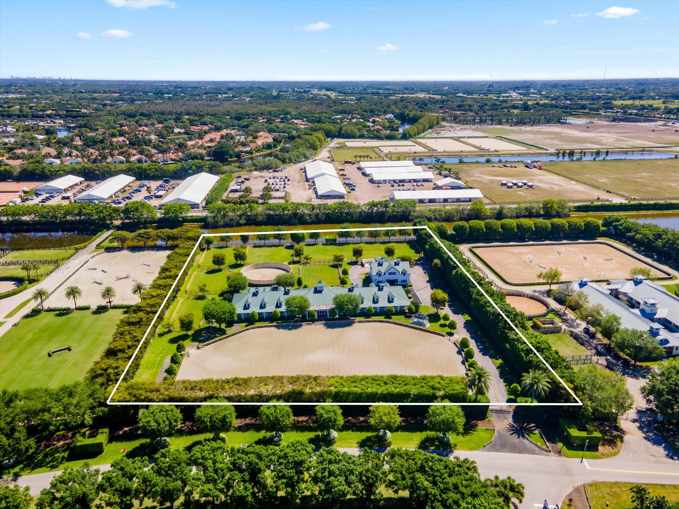 This top-tier equestrian estate located in Wellington's Grand Prix Village, features 24 stalls with water access, 4 grooming stalls, 6 large grass paddocks, and a 150x270 Martin Collins arena. Additional highlights include an 8x32 round pen, 3-bay covered wash rack, spacious viewing porch and gazebo. The center aisle barn offers a tack room with full bath, feed room, and ample storage. Owner's lounge features a full kitchen, office, and bathroom. A separate storage building houses equipment and laundry facilities. 2 apartments upstairs feature 3 bedrooms and 3 full bathrooms. With full security, Generac generator, and gated entrances, this farm is move-in ready for serious equestrians.