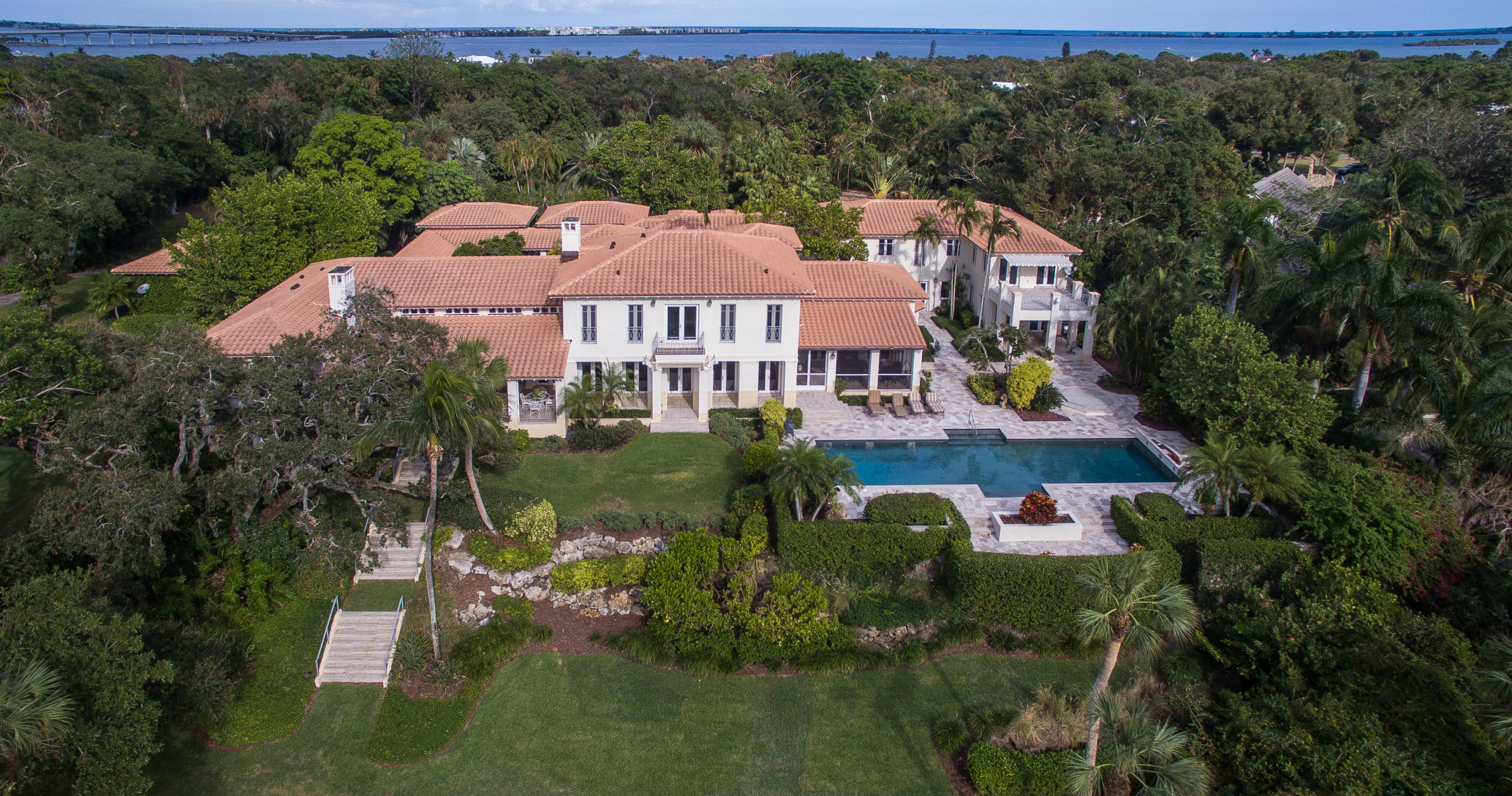 Sitting high above the river on 3+ acres offering privacy and plenty of room to roam on the estate caliber grounds and your own inland boat basin with 300' of river frontage. The sprawling main home feels palatial, yet not overwhelming and all of the bedroom suites are thoughtfully placed to offer plenty of privacy. Stroll through the tranquil courtyard before entering into a grand living room overlooking the river. As you walk through the gallery you'll discover a library, richly accented with black walnut built-ins, a formal dining room, gourmet kitchen, breakfast room, a fully equipped gym...there are just so many rooms to explore! Top it off with a stand-alone movie theater with seating for 15 plus a 2 bedroom, 2 bath caretaker/guest house. Truly a rare find in beautiful Martin County.