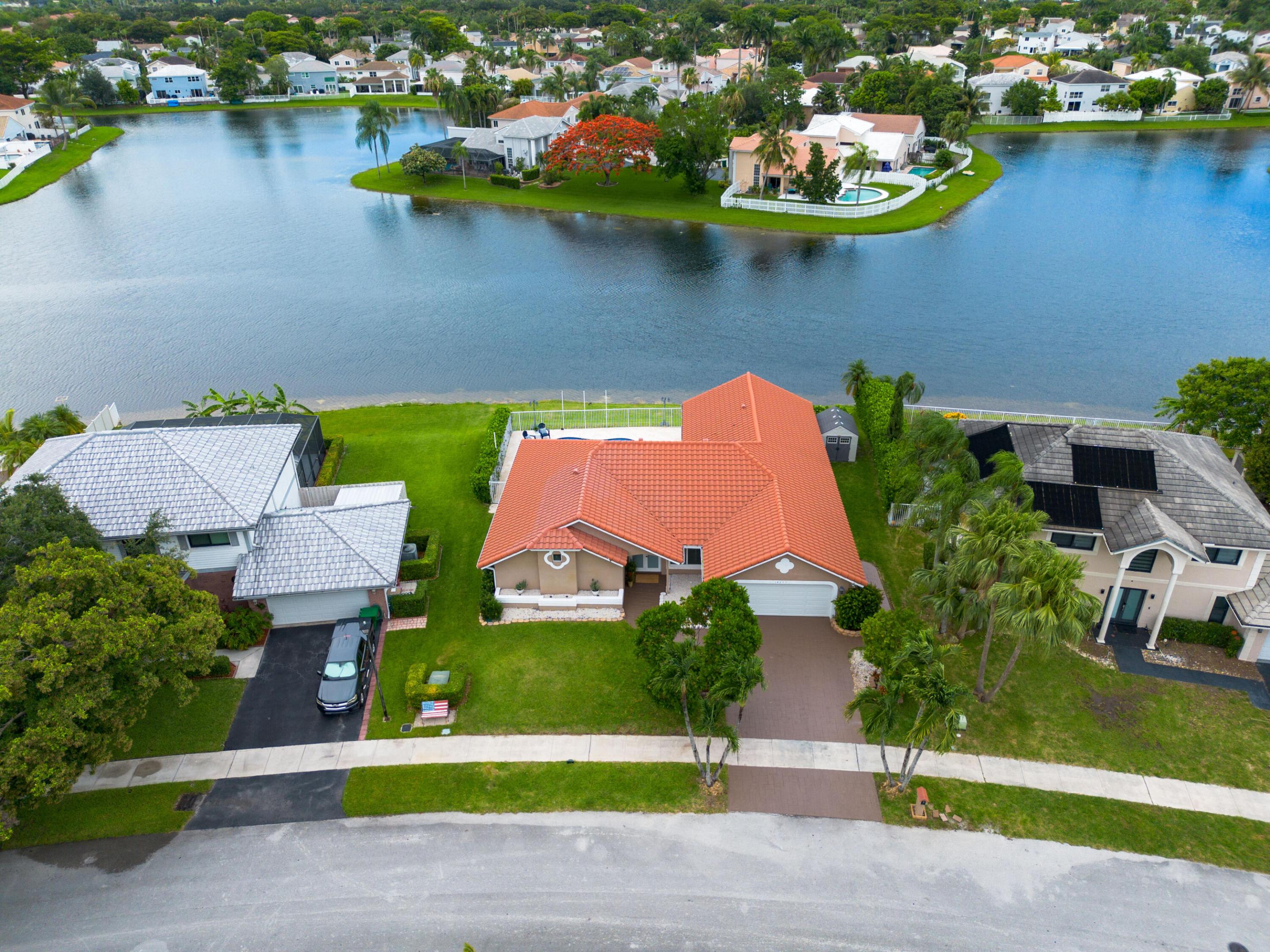 Experience modern South Florida living in this beautifully updated lakefront pool home located in the desirable Shenandoah community. Situated on a generous 9,558-square-foot lot with a low HOA, this 4-bedroom, 2-bathroom residence offers 2,154 square feet of bright, open living space. The interior features luxury vinyl plank flooring, plantation shutters, updated lighting, and smooth ceilings. A custom chef's kitchen stands at the heart of the home, complete with a large granite island and sleek finishes. The primary suite serves as a private retreat, showcasing a fully remodeled bathroom with Carrara marble, a free-standing tub, and a custom walk-in rainfall shower. Major structural upgrades provide complete peace of mind, including a newer roof, full impact-rated windows and doors,  a newer HVAC system, and an updated water heater. Step outside to a backyard oasis featuring a refinished pool with blue quartz aggregate finish, and an extended travertine patio. Enjoy panoramic lake views and outdoor entertainment space under the covered patio. Conveniently located near major highways, Sawgrass Mills, the Amerant Bank Arena, and local beaches, with quick access to Fort Lauderdale-Hollywood International Airport. Professional photos coming soon. Schedule your tour today!