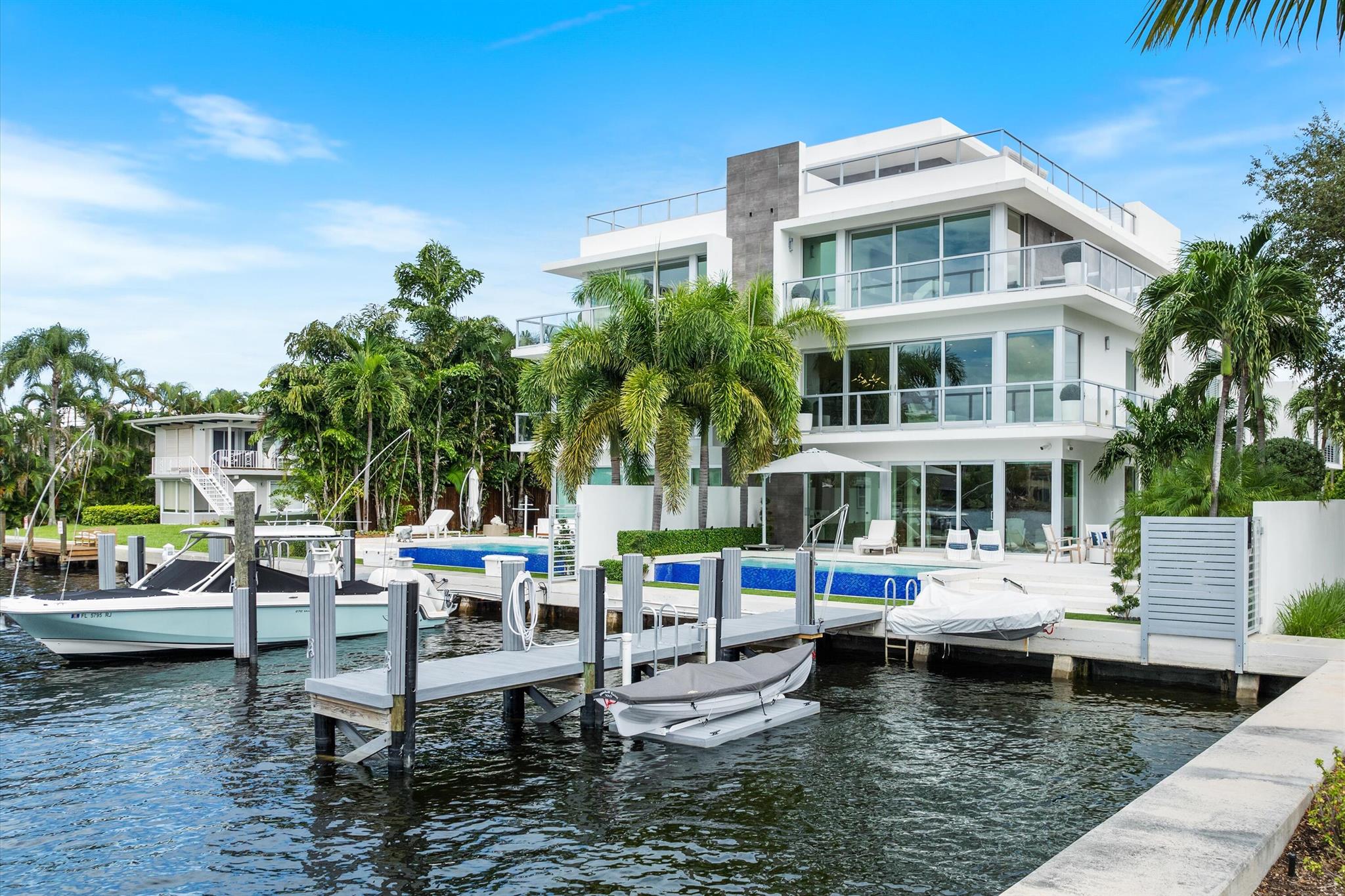 Welcome to Nautica Delray, an exclusive enclave of four luxury townhomes designed by award-winning architect Richard Jones, built in 2019 by Seaside Builders with the interior of this home artistically enhanced by SPACE dfi. This coastal modern masterpiece offers a private waterfront lifestyle with a personal dock, just steps from the ocean and minutes from vibrant downtown Atlantic Avenue with its fine dining, boutique shopping, and entertainment. This stunning 4 bedroom, 4 1/2 bath  townhome is designed for refined living, featuring a club level, main level, primary bedroom level, and a rooftop terrace offering panoramic views. Enter through the club level, where Travertine flooring and sleek interiors welcome you. This level includes an ensuite bedroom, currently utilized as an office, with direct access to the private infinity pool. The space is outfitted with a Murphy bed and built-in desk for maximum functionality. The ensuite bathroom features quartz countertops and a cast concrete sink. This level also boasts a stone accented gas fireplace, a custom coffee wet bar with beverage cooler, a discreet "shoe shed", and an elegantly designed laundry room with Electrolux appliances. The main level offers an open-concept great room, combining a well appointed custom kitchen with Miele appliances, a spacious living room, dining area, and another ensuite bedroom. The perfect space for entertaining or family gatherings. On the primary bedroom level, the suite is a true retreat, featuring a private wraparound balcony with a fire pit and breathtaking views of the Intracoastal. Fully retractable sliders open to create seamless indoor-outdoor living, enhancing the waterfront experience. The luxurious primary bathroom includes a "water room," complete with a soaking tub and enclosed shower, wrapped in privacy glass to flood the space with natural light while maintaining seclusion. Dual sinks set in floating cabinets combine sleek design with practicality. An additional ensuite bedroom with added square footage on this level adds flexibility, while a second laundry closet with Electrolux appliances completes this floor. The rooftop terrace is the pinnacle of luxury, with sweeping vistas of the surrounding area, a full summer kitchen with natural gas grill and fridge, and a Hot Springs Jetsetter hot tub. This is the perfect setting to enjoy al fresco dining and views of the winter holiday boat parade, summer fireworks, or simply unwind after a long day. This home is also equipped with Savant smart home technology, integrating security, lighting, televisions, and surround sound throughout the home. Other highlights include a private elevator, floor-to-ceiling windows, Hunter Douglas Silhouette shades, and a combination of Travertine and luxury ceramic tile flooring. Of the four homes in this boutique community, only two have private docks, and this one includes 50 feet of frontage in a no-wake zone, accommodating vessels up to 45 feet. The slip, in a protected basin on the Intracoastal, includes a 150 lb. capacity manual lift and a 5'x8' floating AccuDock for direct water access with a small personal watercraft. The private 24' x 9' infinity pool is surrounded by Travertine decking and features a Sonance Garden Series sound system with a subwoofer and eight satellite speakers, all integrated into the Savant Sonos system. Another fire pit completes this luxurious outdoor oasis. Exquisite craftsmanship and detailed architectural touches make this timeless modern home a rare find. Ideal for the discerning buyer seeking unparalleled luxury and waterfront living in paradise.
