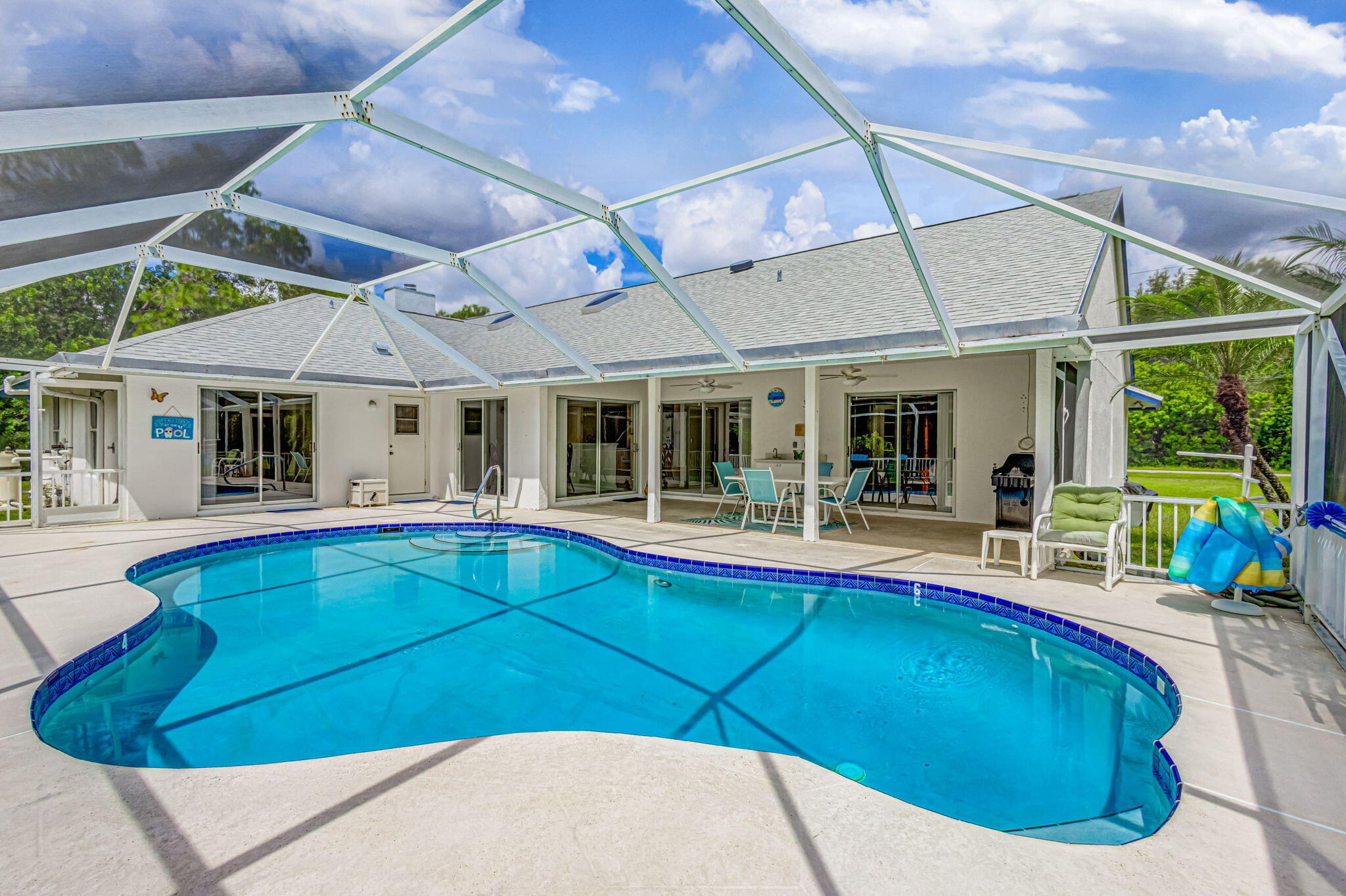Beautiful 3BR/2BA pool home available for rent on a spacious lot in desirable Jupiter Farms. This light-filled home features soaring vaulted ceilings, skylights, and an open-concept floor plan with sliding glass doors from the kitchen, both dining areas, and the primary suite, creating seamless indoor-outdoor living. Enjoy your private backyard oasis with a sparkling screened in pool, stocked fishing pond, mature mango tree, orange tree, and plenty of room for your boat, RV, or other recreational vehicles. Freshly painted interior with updated light fixtures and a reverse osmosis water filtration system serving the kitchen and refrigerator. Experience the privacy, tranquility, and country charm of Jupiter Farms while enjoying all the comforts of Florida living.
