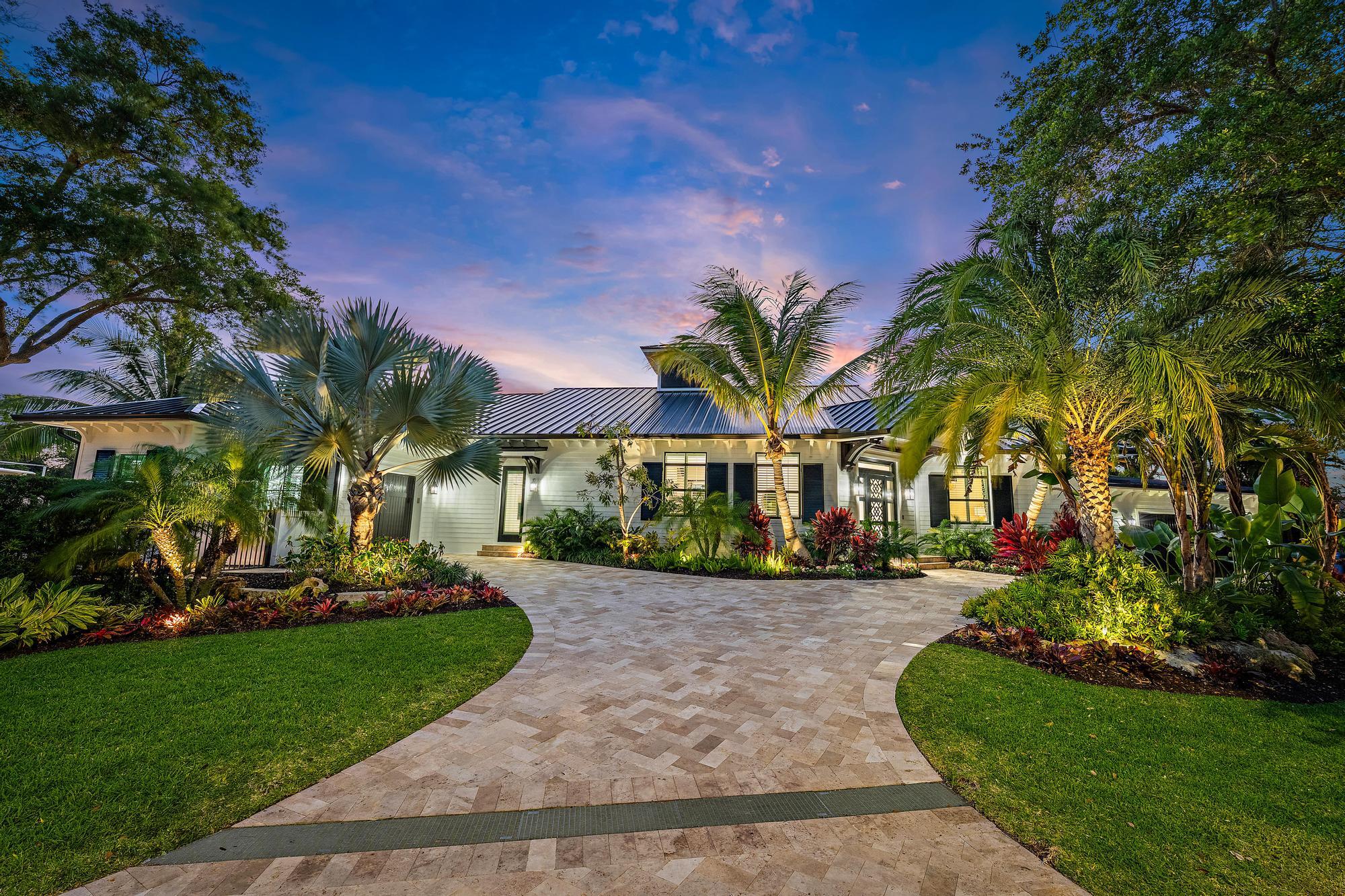 Your Private Tropical Oasis Awaits in Jupiter, Florida. Welcome to an extraordinary waterfront estate where timeless elegance meets modern coastal luxury. Fully rebuilt in 2023 and offered completely furnished, this exceptional residence is paired with an adjacent lot, providing nearly 400 feet of pristine shoreline—a truly rare and distinguished offering.  Encompassing 4 bedrooms, 4.5 bathrooms, and 4,145 square feet under air (nearly 6,800 total square feet), the home has been thoughtfully curated with impeccable attention to detail and elevated finishes throughout.   The primary suite serves as a serene private retreat, featuring a balcony overlooking the water, an expansive walk-in closet, and a spa-caliber bath complete with a walk-in shower, soaking tub, and dual vanities.  Designed to impress, the chef's kitchen is outfitted with premier appliances from Wolf, Sub-Zero, and Cove, anchored by an oversized center island with integrated seating—ideal for both intimate gatherings and grand entertaining. Elegant plantation shutters, custom window treatments, and designer chandeliers enhance the home's sophisticated aesthetic.  Additional features include:  Dining room with seating for eight, an expansive laundry suite with premium Speed Queen appliances, a dedicated dog washing station, and auto-fill pet system. Garage area includes 5 total spaces, a double-deep garage accommodating up to four vehicles, complete with a secondary laundry area, and an additional garage complemented by a full wet bar. Peace of mind is built into every detail, from the exterior camera system to the whole-house generator with an automatic transfer switch, delivering uninterrupted power and effortless security around the clock. Outdoors, a resort-inspired setting awaits. The covered lanai is appointed with motorized screens and multiple dedicated TV viewing areas, creating the ultimate outdoor entertainment experience, along with a fully equipped summer kitchen featuring a Wolf gas grill and pizza oven. The pool and spa are enhanced by a dramatic stone grotto waterfall with integrated seating, gas tiki torches, a firepit lounge, and a sanded relaxation area evoke a private island ambiance.  For the discerning boating enthusiast, the property includes a 70-foot dock with a High Tide 20,000 lb lift, and the adjacent lot offers two additional piers—ideal for accommodating smaller watercraft and paddleboards. Home completely rebuilt in 2023, and attached to a previously built addition built in 2010. This exceptional waterfront estate offers a rare combination of luxury, space, and lifestyle—an absolute must see!