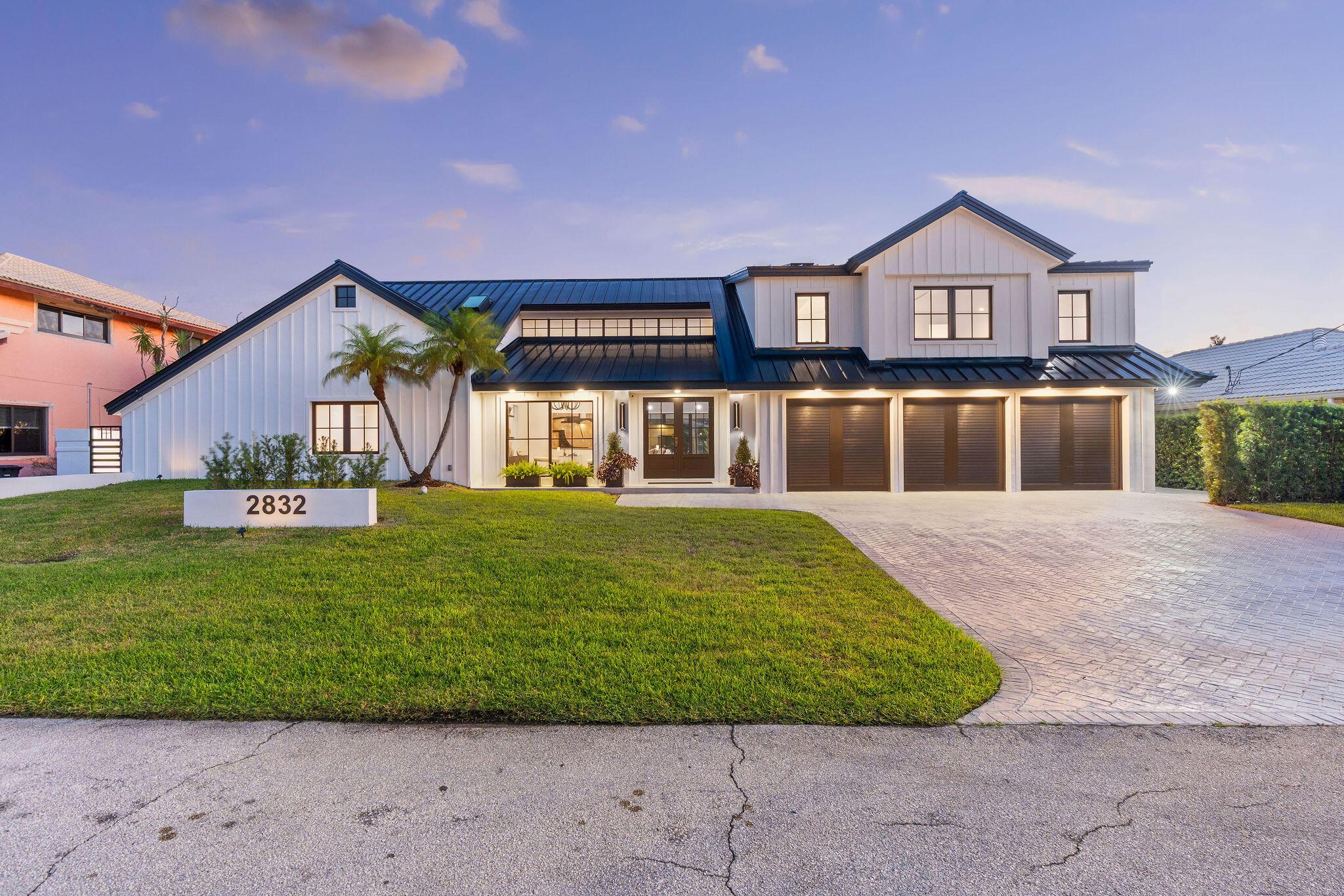 Step into this fully updated and meticulously renovated, transformed from the roof to the foundation, including every finish encompassed within - that is home at 2832 NE 37th Court. The curved, newer white architecture, and all black crested roofing, embodies the marking of a powerful statement piece seen by land, sea, or air. This rare, modern luxury, farmhouse estate, lies on a spacious 10,000 square foot lot, with 100' waterfrontage. Designed by a 360-lens seeking rarity, edge, elegance, glamour, and simplicity combined, this 5-bed, 5.5 bath estate brought that vision to real-life. The moment guests enter, they are captivated by the near floor-to-ceiling, cascading crystal chandelier. Downstairs office/den can easily be converted to a bedroom, complete with a built-in closet. The neutral tones are evident in the waterfall countertop and sparkling bar both handcrafted in Italy, seamlessly blending the more modern, dark toned finishes throughout. A pristine, yet poetic pairing of femininity and masculinity. The main foyer presents a chic, open and airy concept, creating the ideal space to relax or entertain, amongst views of the glimmering waterfront, resort-style pool, spa, and serene palm trees. Step just outside to the renowned, *Non-Mandatory* Coral Ridge Country Club, within a brisk walk, nestled perfectly in the heart of Fort Lauderdale - the yachting capital of the world. This city offers a vibrant seaside culture and premier entertainment trifecta of watersports, golfing, and stunning beaches. This rare, custom farmhouse estate, is right in the center of it all. Featuring: 2-luxury suites; 1st-floor primary suite, 2nd-floor multigenerational suite, exclusive full cabana bath, metal roof, state-of-the-art- finishes and appliances i.e. Italkraft's Kitchen Design (designs featured at Four Seasons FLL and Baccarat Miami Residences) Dacor's Innovative Luxury Smart Kitchen with Dual-Fuel Steam Range propane stove, dual dishwashers and wine cellars, camera enabled refrigerator to connect to your smart phone, Kohler's Smart Bath systems and floating art-deco faucet, whole home generator, central vac, impact windows and skylights throughout, and more.