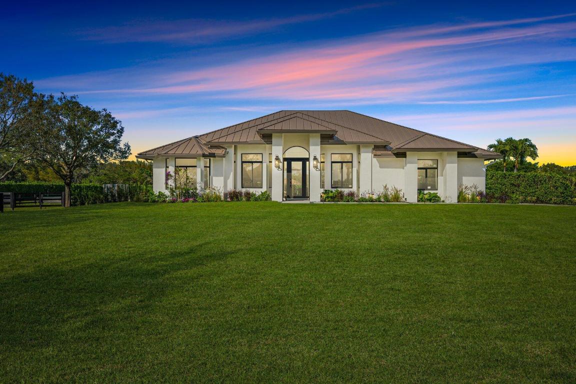Designer-Perfect Gated Estate on 2+ Acres in Prime Saddle Trail. Welcome to 2920 Appaloosa Trail, a stunning one-of-a-kind residence that will impress the most discerning homeowners and equestrians. This modern showcase was fully remodeled in 2023 with attention to every detail, from the carefully-chosen color palette to the thoughtfully-selected finishes. The fully-fenced property with indoor-outdoor entertaining is ideal for the equestrian lifestyle. The dramatic great room boasts an effortless flow, creating a lovely environment for everyday living. An open-concept kitchen will be the heart of the home, showcasing custom-built white-oak cabinetry, top-of-the-line Monogram appliances, a six-burner gas stove, large hidden walk-in pantry, quartz countertops, and a large center island. Hardwood floors grace the entire home, complemented by vaulted ceilings and hurricane-impact windows &  doors. A cozy fireplace, 85" built-in Sony TV, and recessed speakers enhance your experience. The glamorous master suite is perfect for relaxing with its freestanding tub, luxurious shower, and custom his-and-her vanities. Second and third bedrooms are completely reimagined for guests and family. Step outside to the expansive 500 square-foot covered patio featuring custom BBQ, gas fire pit, and views of the 162' X 180' arena and private grounds. The centerpiece of this estate is the new 11-stall barn, complete with an air-conditioned tack & laundry room and generous storage capacity. The staff quarters includes one bedroom, one-and-a-half baths, and its own spacious garage. The all-weather irrigated riding arena is adjacent to the barn, ensuring a perfect setting for all equestrian pursuits. Just a short hack to Wellington's International Equestrian Center, this special home is "The One" you've been waiting for. Will not last. Fully furnish
