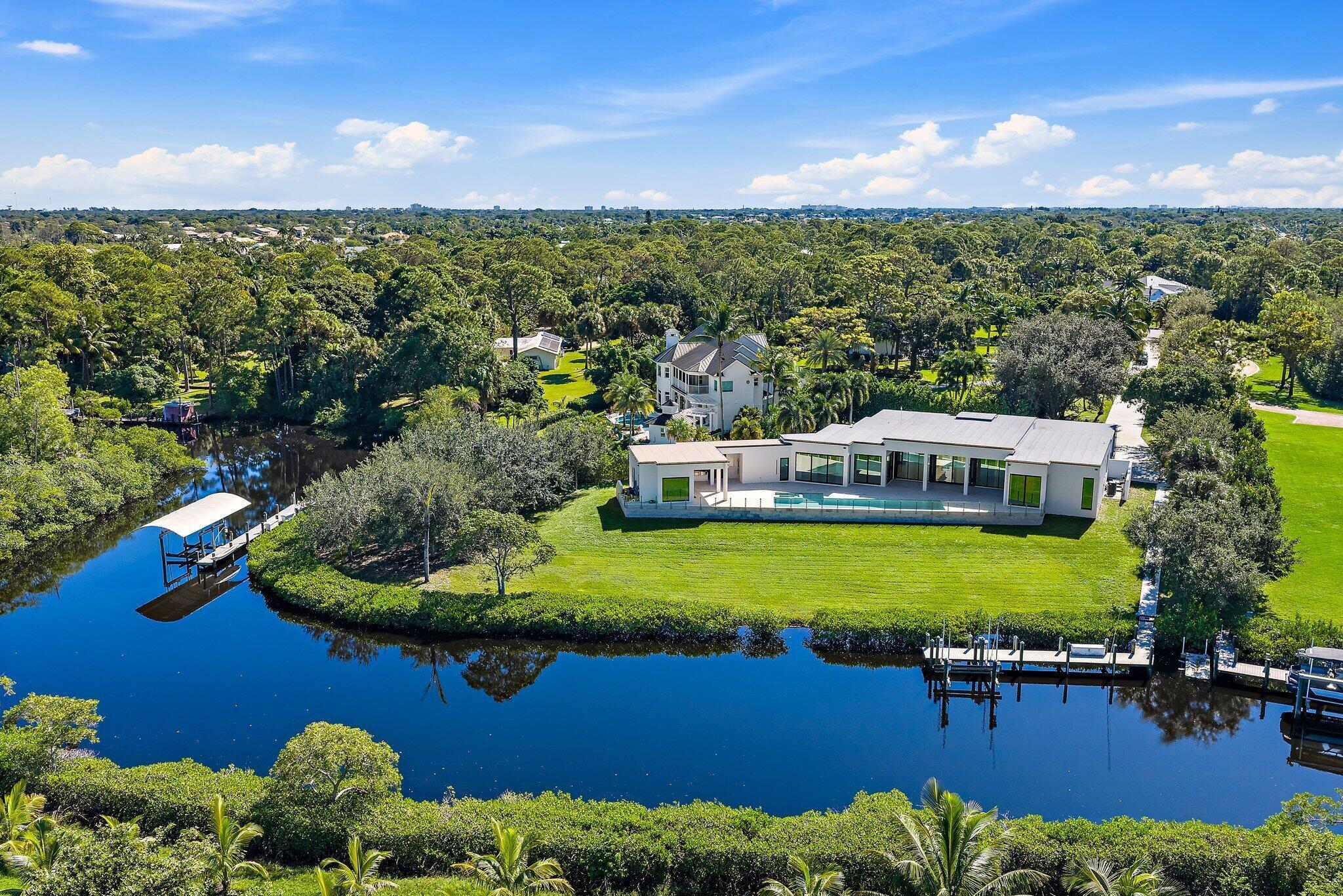 Newly completed in 2025, this exceptional waterfront estate sits on over two private acres along the North Fork of the Loxahatchee River. Thoughtfully designed with clean architectural lines, curated finishes, and seamless indoor-outdoor living, the residence offers a rare combination of modern construction and expansive grounds--recently repositioned to $6,495,000. The home features four bedrooms and four-and-a-half baths with soaring ceilings and walls of glass that frame tranquil river views. The chef's kitchen is appointed with a Wolf range, Miele built-in coffee system, Subzero fridge and wine fridge, custom cabinetry, and an oversized island designed for entertaining. Open living and dining spaces flow effortlessly to covered outdoor areas, creating a year-round waterfront lifestyle. The primary suite is privately situated and offers serene views, a spa-inspired bath, and generous custom closets. Each guest suite is well-proportioned and en-suite, providing comfort and privacy for visitors alike. Outdoors, the scale of the property allows for privacy rarely found on the river. The expansive grounds offer room for future enhancements--guest house, sport court, or additional recreational amenities--while maintaining a secluded estate setting. A private dock with 16,000-pound lift provides convenient boating access with one fixed bridge to the Intracoastal. Whether enjoying quiet mornings on the river or entertaining at sunset, this property captures the essence of Jupiter waterfront living. A recent land acquisition in the neighborhood of similar size traded for $3.3 million, making this completed home a smart investment. An uncommon opportunity to secure new construction, acreage, and boating access in one of Jupiter's most desirable waterfront corridors.