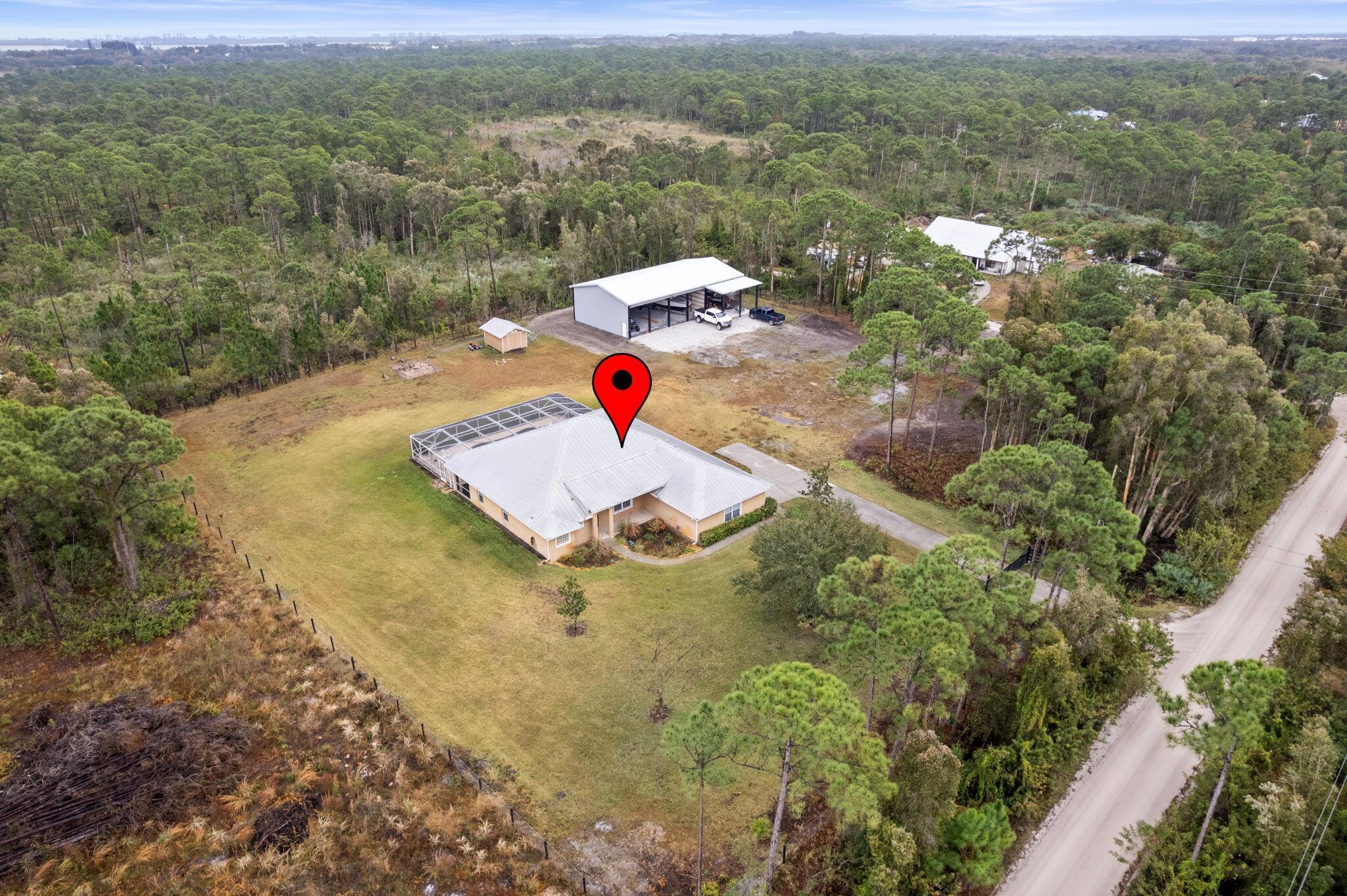 Enjoy peaceful country living on 2.1 private acres in North St. Lucie County. This well-maintained property offers a 3-bedroom, 3-bathroom home featuring two master suites, ideal for multi-generational living or guest accommodations. The home includes a screened saltwater pool overlooking serene, undeveloped land. Interior features include a fully furnished setup, updated A/C and water heater (2022), and a durable metal roof. Outdoor amenities include a fire pit area, fully fenced property with dual entrances, and an automatic gate. Large 40x72 hurricane-rated shop with electric, perfect for storage, hobbies, or business use. County taxes only. Conveniently located approximately 15 minutes from the Indian River lagoon, emerald beaches , Vero Beach and downtown Ft. Pierce.