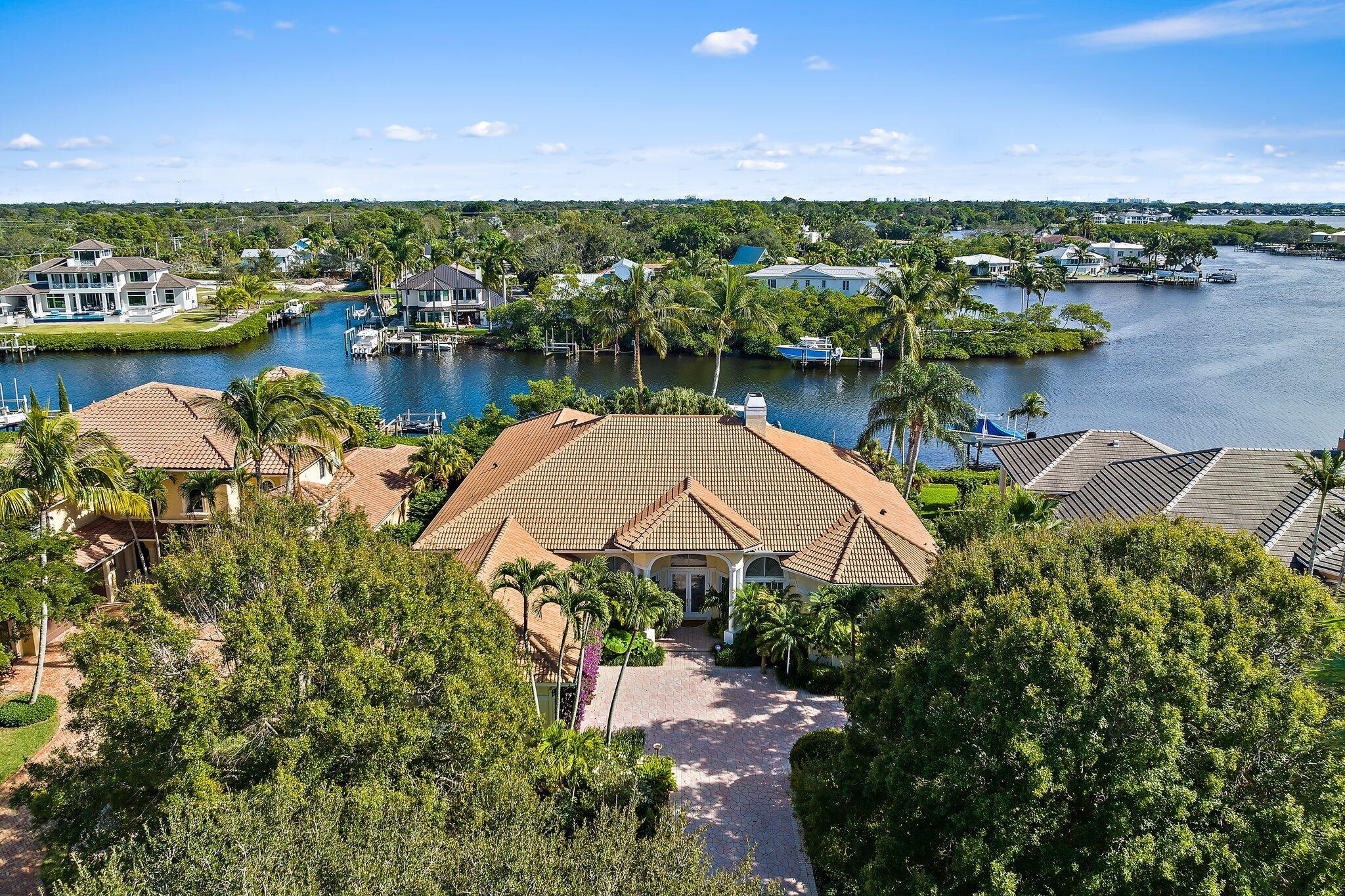 Nestled within the prestigious community of Islands of Jupiter, 18829 SE Windward Island Lane is a waterfront oasis offering unparalleled luxury and comfort. This exquisite residence spans 4,193sq ft of living space with a total of 5,813sq ft, featuring 4 bedrooms, 3 full baths, and 1 half bath, as well as an office/den and a 2-car A/C garage. Situated on an expansive .43-acre lot along the serene Loxahatchee River, this home is a boater's dream, boasting a private dock equipped with two boat lifts one 16,000lb lift, and the other is a 12,000lb lift. Additionally, a dual float-on jet ski dock adds to the waterfront allure. The outdoor living space is a true haven, featuring a heated pool and spa. An outdoor kitchen, complete with a grill, sink, ice maker, & beverage center, SEE MORE... caters to alfresco entertaining. Enhancing the ambiance is an outdoor fireplace, creating a captivating setting for enchanting evenings under the stars. Inside, the kitchen is a culinary masterpiece with quartz countertops, high-end stainless-steel appliances, custom wood cabinetry, decorative lighting, and a central island. The spacious primary bedroom offers scenic views of the waterway, and its en-suite bathroom is a spa-like retreat, featuring a separate tub and shower, along with dual sinks. The three additional bedrooms are generously sized and 2 of them are equipped with walk-in closets, ensuring ample storage space. The home is adorned with plantation shutters, ceiling fans, a gas fireplace, built-in shelving, and decorative lighting. Notable features include partial impact windows and a whole house generator for added peace of mind.
For boating enthusiasts, direct access to the Intracoastal Waterway and the Atlantic Ocean is a coveted amenity. The vibrant city of Jupiter, Florida, offers a myriad of attractions, including waterfront restaurants, cultural events, and outdoor activities. Residents can enjoy the perfect blend of upscale living and natural beauty in this sought-after community. Welcome to a waterfront lifestyle that epitomizes luxury and convenience in the heart of Jupiter.