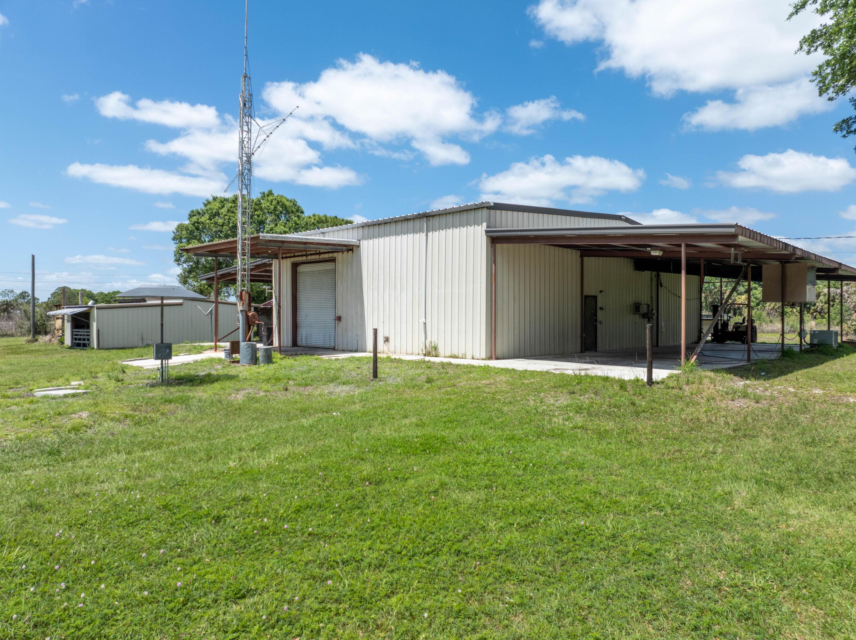 This Rare 5-acre parcel, is an exceptional opportunity for hobby farming, equestrian use, craftsman in need of a large functional workshop, or private single family estate development. Zoned AG-5 with multiple outbuildings, this property is ideal for someone seeking rural privacy with a versatile, ready-to-use 5,108 sq. ft. metal barn with finished interior spaces containing a Machinist workshop, Gigantic open workspace with high ceilings, Storage bays. Kitchen with basic amenities: stove, refrigerator and stainless industrial counters. A loft area with a Bedroom, Bathroom and an Office space. The property is also contains multiple extra storage structures and AG-5 zoning, which supports a variety of agricultural and residential plans. Build a single-family residence, operate small-scale  farming or livestock, convert to a fully equipped man cave, workshop, compound, or a secure prepper's hideout. Conveniently located on Glades Cut Off Road in Port St. Lucie — blend of rural seclusion and access to local amenities.