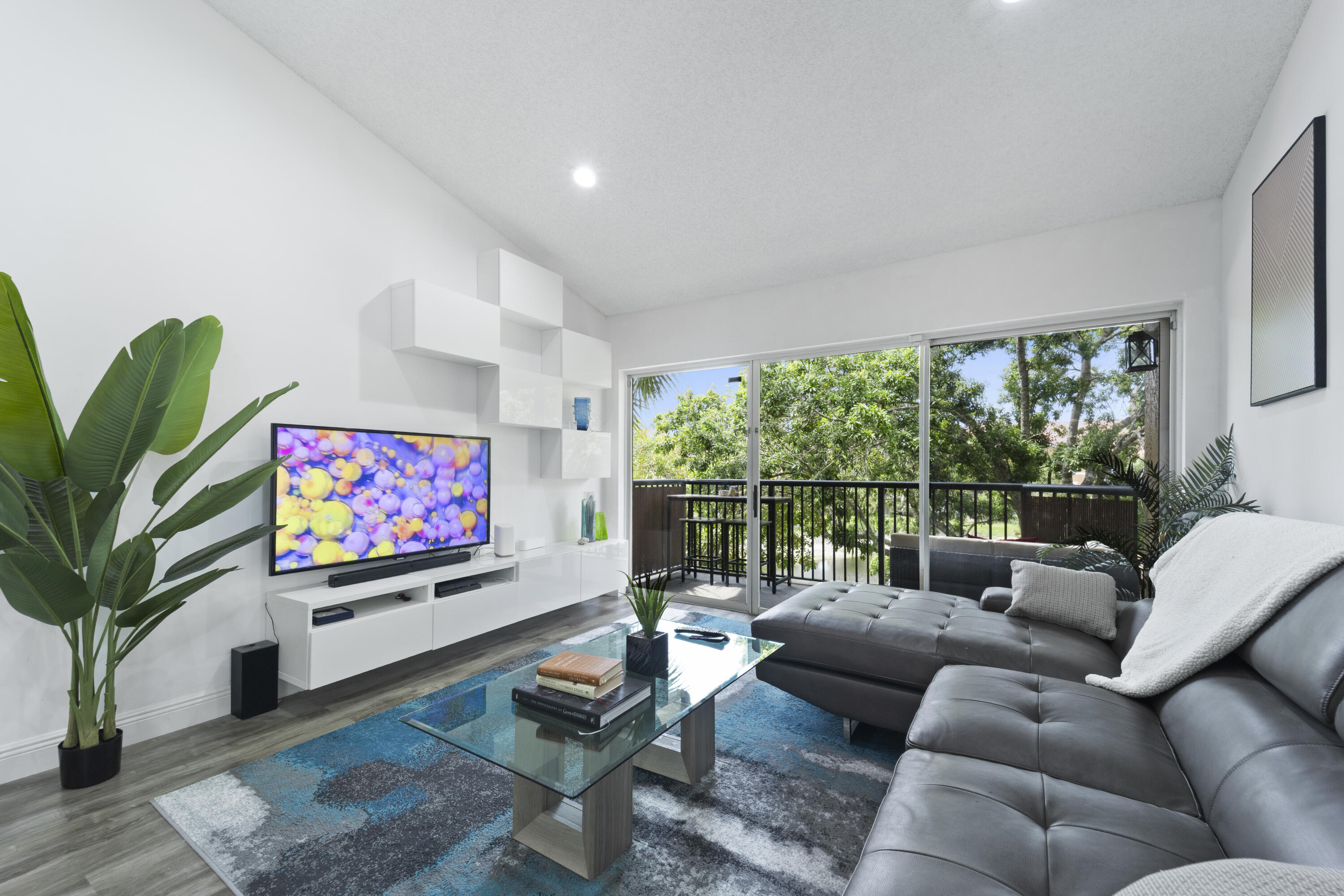 Welcome to one of the most desirable 2-bedroom, 2-bathroom residences in Edgewater at Coral Springs. Located in highly sought-after Building 9, this beautifully renovated top-floor condo combines modern upgrades, peaceful water views, and one of the most convenient locations in the entire community.  Positioned closest to the main entrance, Building 9 offers unmatched ease of access with minimal driving once inside the gated community. The unit also comes with an oversized assigned parking space located directly in front of the stairs and elevator, making everyday living exceptionally convenient. Even better, Building 9 is adjacent to the community's only trash compactor, allowing you to simply walk downstairs rather than drive your trash across the neighborhood like most residents.  Inside, soaring vaulted ceilings and abundant natural light create an open, airy atmosphere that immediately feels larger and more inviting than lower-floor units. The fully renovated interior features gray wood flooring throughout, recessed lighting, upgraded bathrooms, and a stunning modern kitchen with white shaker cabinetry, stone countertops, and stainless steel appliances.  The spacious living room flows seamlessly onto a private balcony overlooking the lake and pool, offering peaceful views and noticeably less road noise than units facing the parking lots and Wiles Road. Newly installed privacy fencing on the balcony enhances the outdoor living experience, creating the perfect setting for morning coffee or evening relaxation.  Additional upgrades include a Nest smart video doorbell, Yale keyless entry system, Nest smart thermostat, Google Nest Mini speakers, smart lights, professionally concealed TV wiring, modern wall-mounted cabinetry for additional storage, and a newer A/C system installed in 2022. The oversized primary closet adds even more functionality to the space.  For buyers offering asking price, the condo can be sold fully furnished and fully equipped with its smart home features, making this an exceptional turnkey opportunity for both owner-occupants and investors alike. Edgewater allows immediate rentals with no waiting period, and the included furnishings make this a rare move-in-ready or rental-ready opportunity without the added expense of furnishing the unit yourself.  This is more than just a renovated condo — it's one of the best-located and most thoughtfully upgraded units in all of Edgewater.