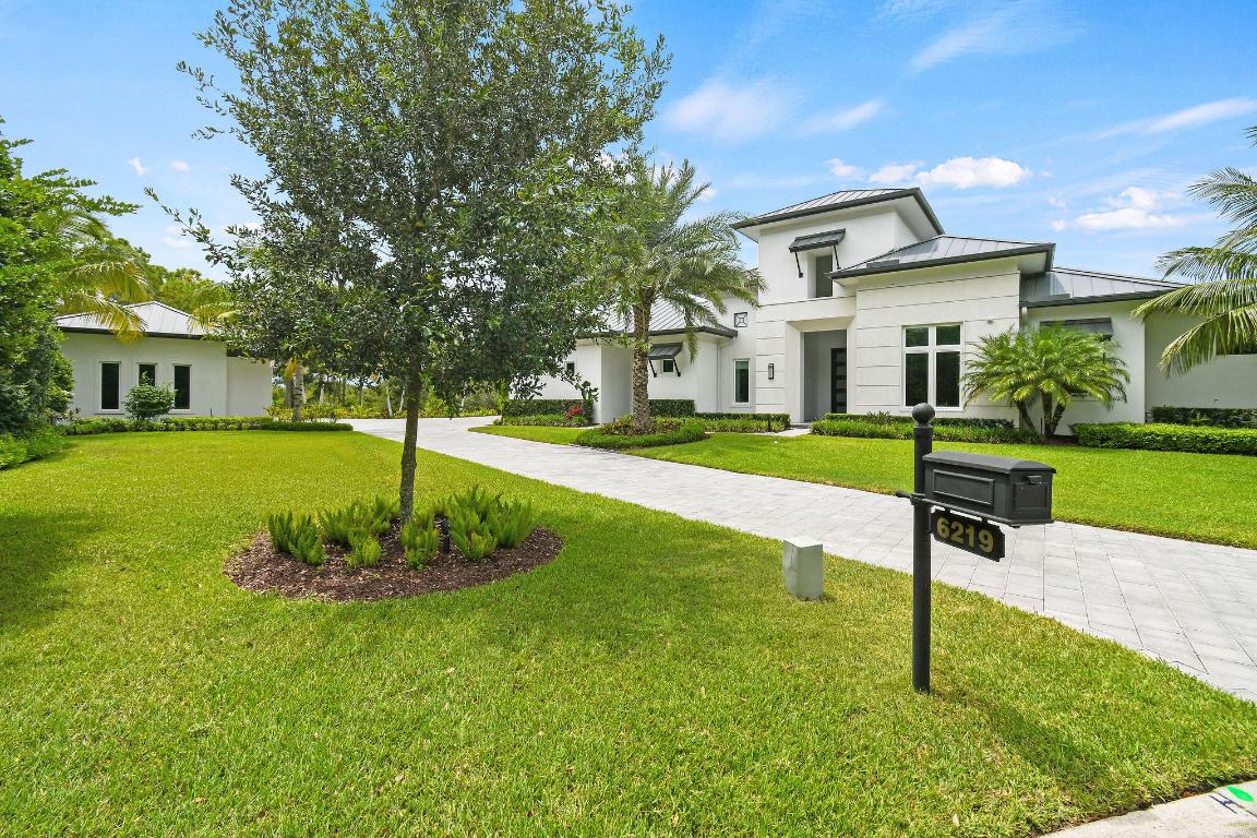 This exquisite residence, designed and built by the prestigious AR Homes in 2021, is situated on a spacious lot and a half, totaling just over 3/4 of an acre. With 9,000+ total square feet, and over 5,800 living square feet, the home features 4 bedrooms, including an attached mother-in-law/guest suite, 4 full bathrooms, 2 half baths, a club room, and 7 air-conditioned garage spaces. The open-concept layout blends indoor and outdoor living. Both the grand living room and club room open onto a large covered and screened pool deck, showcasing a stunning pool and spa, summer kitchen, and tranquil lake views. The gourmet chef's kitchen is equipped with top-of-the-line appliances, custom cabinetry, and a generous center island, ideal for meal preparation and entertaining. A detached, air-conditioned 5-car garage offers ample storage and convenience. Located in the exclusive Medalist Village, this home offers a true country club lifestyle. Residents enjoy access to a championship-designed 12-hole par-3 golf course, The Aussie Pub, The Medalist Village Spa & Clubhouse, tennis courts, and state-of-the-art fitness facilities. Whether you're a golf enthusiast, fitness lover, or simply enjoy an active social scene, this exceptional community delivers an unparalleled luxury experience.