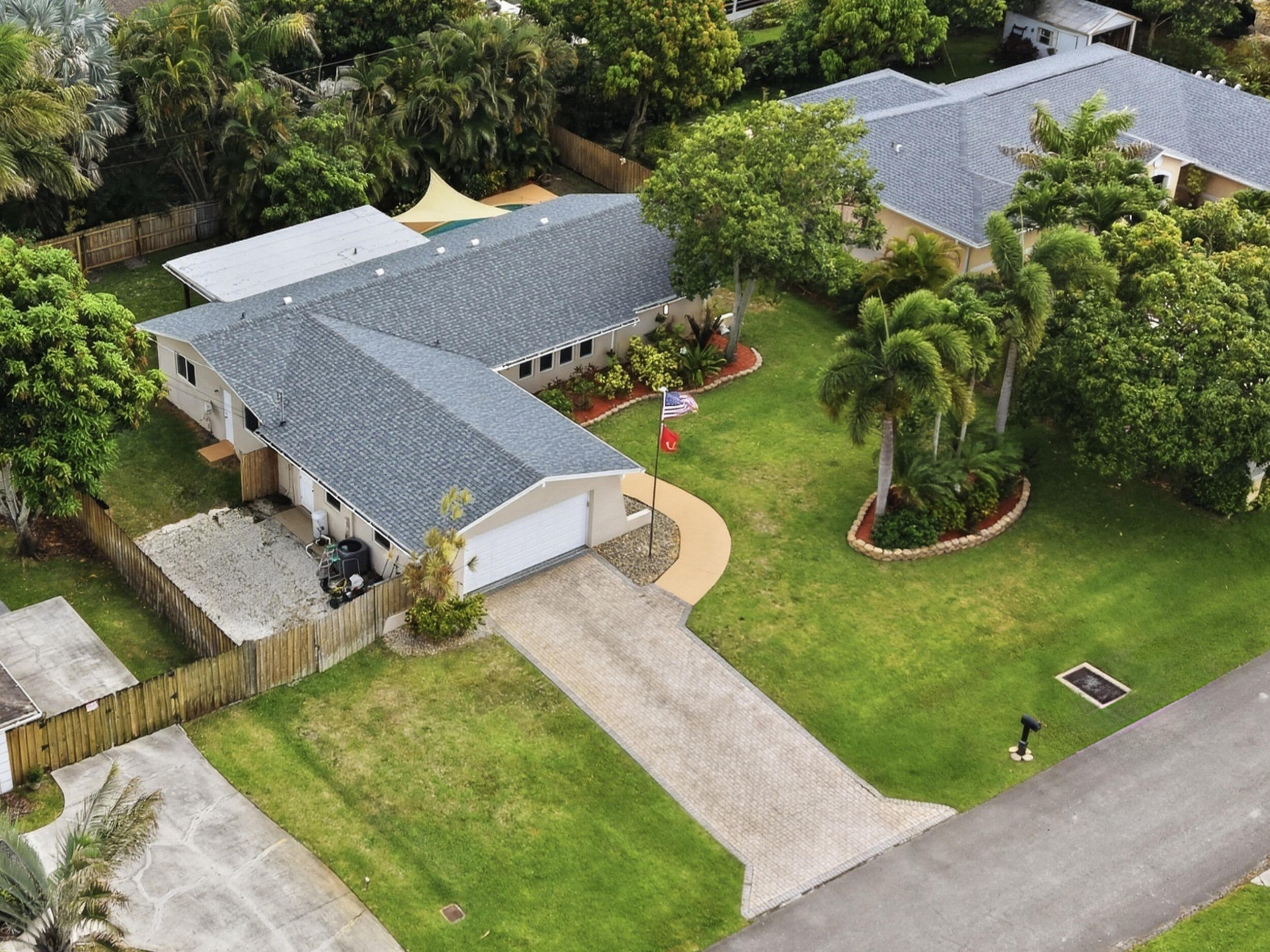 Welcome home to this beautifully updated 3-bedroom, 2-bathroom, 2-car garage open-concept pool home located in the highly desirable, no-HOA community of Florida Gardens. Situated on just over a quarter acre, this property perfectly captures Florida charm while offering an exceptional blend of comfort, style, and functionality.  Notable updates include a brand new roof (2026) and a brand new A/C system (2025), both with transferable warranties, full impact glass throughout the home (2018), and a fully renovated kitchen, bathrooms, and flooring completed in 2020. The garage is equally impressive, featuring full built-ins and custom cabinetry for exceptional storage and organization.  From the moment you arrive, you'll notice the lush tropical landscaping and expansive brick paver driveway,  along with additional drain rock parking on the side of the home, perfect for a boat, RV, or all your Florida toys. Inside, the home continues to impress with large square tile flooring throughout the main living areas, recessed lighting, updated trim work, farmhouse-style doors, and an abundance of natural light throughout.  The beautifully renovated kitchen serves as the centerpiece of the home and features an oversized island with bar-top seating, modern pendant lighting, solid wood shaker cabinetry, granite countertops, decorative tile backsplash, recessed lighting, stainless steel appliances, an oversized sink with updated hardware, and a large impact pass-through window opening directly to the patio area. The kitchen also includes a dedicated coffee and snack bar area, as well as impact sliding glass doors leading to the pool.  The living and dining areas flow seamlessly from the kitchen, offering ample space for entertaining with updated fixtures, decorative trim work, and plentiful windows that provide exceptional natural light. The living room is highlighted by a decorative wood accent wall, creating the perfect focal point for the space. Conveniently located off the dining area is a spacious laundry room complete with a newer washer and dryer, rustic wood folding station, and built-in cabinetry.  The generously sized primary suite features tile flooring, updated trim and fixtures, a fully customized walk-in closet with built-ins, and impact French doors leading directly to the backyard oasis. The renovated primary bathroom showcases solid wood cabinetry with granite countertops, an oversized vanity with updated hardware, decorative tile inlay accents, updated lighting, and a fully tiled walk-in shower complete with decorative tile accents, knee shelving, and upgraded fixtures. Just off the primary suite is a conveniently located flex room, ideal for a home office or nursery.  Both secondary bedrooms are generously sized and offer excellent closet space, decorative lighting, updated trim, and abundant natural light through impact glass windows. The secondary bathroom has also been fully updated with solid wood cabinetry, an oversized vanity, recessed lighting, updated hardware, and a fully tiled shower/tub combination with direct exterior access to the backyard and pool area, doubling as a cabana bath.  Step outside to your own private backyard retreat featuring a fully fenced oversized yard, a large covered patio with a decorative tongue-and-groove ceiling, and a beautiful freeform pool with decorative tile edging, creating the perfect Florida-style escape for year-round relaxing or entertaining. Additional side-yard space with durable drain rock creates the perfect setup for extra vehicle parking and outdoor toy storage.  Conveniently located in the heart of Lake Worth, Florida Gardens offers the perfect balance of privacy and accessibility with no HOA restrictions. This home is just minutes from the Florida Turnpike, making commuting throughout Palm Beach County a breeze, while also being conveniently close to Wellington, shopping, dining, grocery stores, parks, and entertainment, all while maintaining the quiet charm and spacious lots that make Florida Gardens so desirable