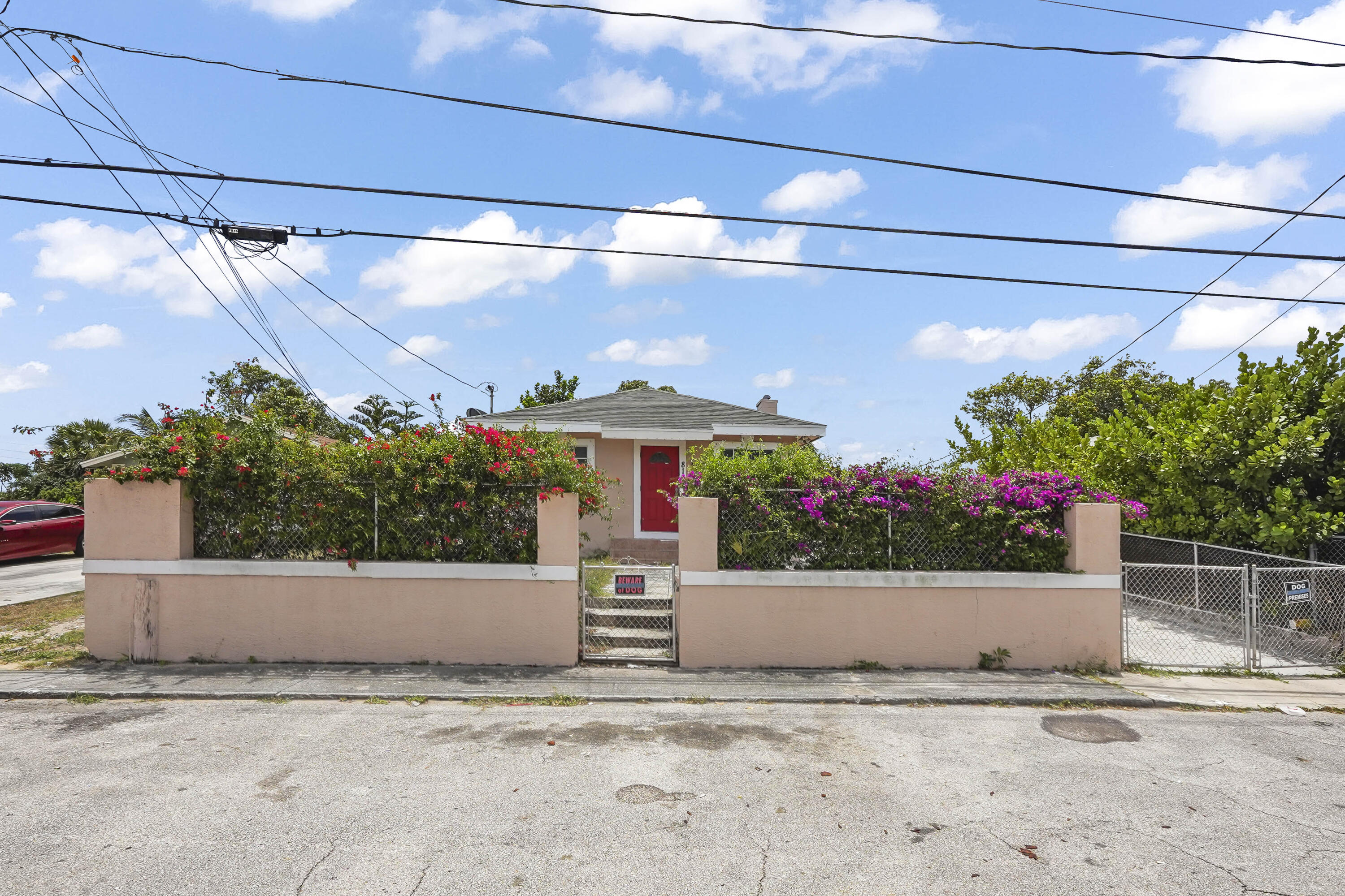 Welcome to a charming single-family home with a fresh peach exterior, vibrant red front door, and lush flowering landscaping that creates an inviting first impression. The fully fenced property offers privacy and functionality with a gated driveway, generous paved parking, covered side area, storage shed, and a spacious backyard shaded by trees with room to garden, entertain, or reimagine into your own outdoor retreat.  Inside, the home offers a bright and flexible layout with open living and dining areas, arched entryways, tile flooring in the main spaces, and abundant natural light. The kitchen features warm wood cabinetry, stainless steel appliances, marble-look countertops, and in-home laundry for everyday convenience. The bedrooms provide comfortable options with closet space,and easy access to the bathroom with clean tile finishes and a walk-in shower. With inviting indoor spaces, practical upgrades, fenced outdoor areas, and plenty of potential, this West Palm Beach home is ready.
