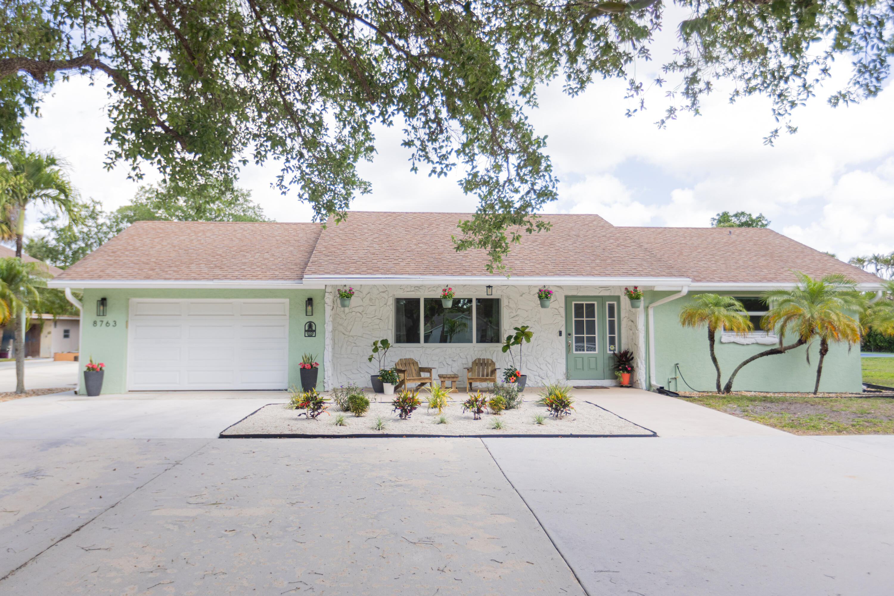 Welcome to your private acre retreat in the highly sought after Palm Beach Ranchettes, one of the few no HOA communities with spacious properties just minutes from everything. This property features a resort style backyard with a brand new saltwater pool and spa, pickleball/basketball court, and private guest building that truly sets it apart. Situated on a fully fenced 1.01 acre lot, the property includes a 3-bedroom, 2-bath main home (2,155 sq ft) with an open living area, spacious kitchen with quartz countertops and a large island, and a split floorplan. The primary suite has a custom walk-in closet, barn door entry, and dual sinks, while the secondary bathroom was fully renovated in 2023. Impact windows and doors throughout provide added comfort and peace of mind. A separate 1,250  sq ft guest house with a large utility garage provides flexibility for guests, extended family, workspace, or creative use. Step outside to a fully screened, oversized L-shaped patio with motorized screens, opening to the custom saltwater sport pool (built in 2024) with marble decking and an above-ground spa, all app-controlled. The property also features a covered pavilion with electric, a professionally installed 30' x 60' pickleball/basketball court, six organic garden beds with irrigation, and a variety of mature fruit trees. Additional highlights include an oversized concrete driveway with room for multiple vehicles, boats, and recreational equipment, all secured by dual electronic gates. Located just minutes from The Mall at Wellington Green, Whole Foods, Trader Joe's, Florida's Turnpike, and A-rated schools, this home gives the rare opportunity to enjoy acreage living with unmatched convenience. This one-of-a-kind property provides a lifestyle that's hard to find in South Florida.