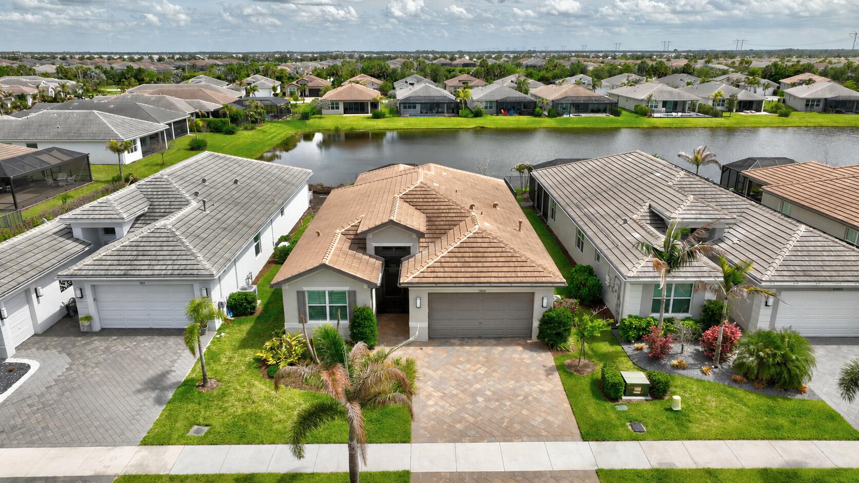FOR SALE in GL Homes' 55+ Valencia Grove at Riverland!  DON'T WAIT A YEAR OR MORE TO BUILD! This beautifully upgraded Atlantica model is available now. This home offers 2,167 square feet under air with 2 bedrooms, a den or optional third bedroom, 2.5 bathrooms, and a 2-car garage. Set on a picturesque water-view lot, you'll love relaxing on the desirable south-facing screened patio, where cooler afternoons and evenings create the perfect setting to enjoy the view. The extended 20' x 19' lanai, complete with a ceiling fan and gas stub-out for a future outdoor kitchen or BBQ, makes indoor-outdoor living effortless. Thoughtful exterior upgrades include a Generac whole-house generator, Aquaman whole-house water filtration system, widened driveway and entry pavers, rain gutters, a screened   front entry, and keyless garage access. Custom etched glass entry doors welcome you into a warm and inviting interior featuring 24" x 24" rectified porcelain tile throughout, faux-painted foyer accents, upgraded lighting, custom dining room mirrors, electric blinds on the sliding patio doors, and a custom entertainment wall enhanced with coordinating tile details. The gourmet kitchen is both elegant and functional, featuring top-of-the-line Level VI Bistra High Gloss Acrylic cabinetry in Starlight White with soft-close doors and drawers, cabinet crown molding, and pantry cabinet doors. Coordinating Pearl Grey backsplash tile, GE Profile appliances, a Bosch dishwasher, reverse osmosis water filtration, and an exterior-vented microwave create a space that is as practical as it is beautiful. Completing the kitchen are a single-bowl stainless steel sink, pendant lighting over the island, and abundant recessed lighting throughout. The primary suite serves as a private retreat with custom-built closets, zebra shades, a faux-painted wall, and tray ceiling accent. The spa-like primary bath features floor-to-ceiling tile, decorative Listello accents, Level IV cabinetry, a frameless glass shower, comfort-height toilet, upgraded faucets, and ceiling-height mirrors.  Additional home highlights include pocket doors in the den, extensive recessed lighting throughout, a floor outlet in the great room, and an upgraded laundry room with a front-load GE washer, gas dryer, and free-standing utility sink. Living in Riverland means enjoying a true resort lifestyle with access to a 34,000-square-foot clubhouse, resort and lap pools, fitness center, arts and culture facilities, miles of walking and biking trails, and a restaurant with a full-service bar. Sports enthusiasts will appreciate the 53 pickleball courts, 15 tennis courts, bocce, and endless clubs, activities, and social events. Conveniently located near Tradition's shopping, dining, and entertainment district, Cleveland Clinic Tradition Hospital, PGA Village, Clover Park for Mets spring training, and the beautiful Treasure Coast beaches. This exceptional home offers the perfect combination of luxury, comfort, and lifestyle. Give us a call to schedule your tour today!