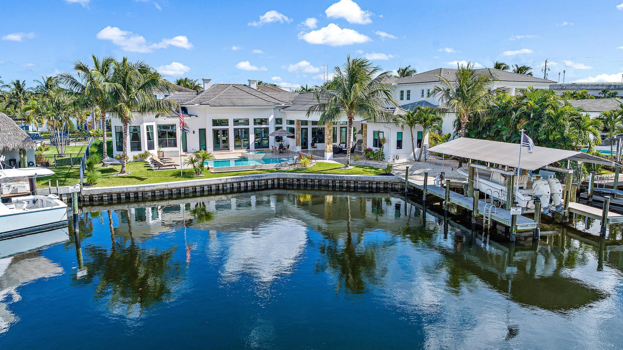 Welcome to this waterfront oasis with over 120 ft of deep water frontage, just one canal from the Intracoastal waterway. Built in 2017, this British West Indies Style home features 4 bedrooms & 4 baths, including a guest home. Step inside where you will be greeted by your majestic great room boasting 16' ft ceilings & sprawling waterfront views.  Just one minute to the intracoastal, this home is a boater's dream featuring a 14k lb covered boat lift & 2 docks. The location & shape of this 1/3 acre lot is at the widest part of the canal, allowing for a better turning radius & more water frontage making it a premium lot in the community! This home was custom built with only the finest of craftsmanship & attention to detail at every turn. Stunning chef's kitchen features a spacious island w/ 3" quartz waterfall edge, high-end appliances, & sleek custom cabinets w/ inlaid TV to create a bold statement in this fabulous kitchen.

This home is designed for entertaining, featuring a saltwater pool & spa, & travertine tile sun deck overlooking the waterway. The outdoor kitchen is equipped w/ TV, hooded vent, ice maker, & phantom screens on the covered lanai. 

The meticulous attention to detail extends to the interior w/ a custom frameless wine display & custom solid doors & trim,  Restoration Hardware light fixtures & hardware, surround sound & rectified wood-look tile throughout. The primary suite offers a private office w/ bay windows. A guest house w/ stunning waterway views comes complete w/ a full bathroom & refrigerator.. Whether enjoying the tranquility of the water or entertaining in your palatial living room, this property is designed for those who appreciate the finer things in life.