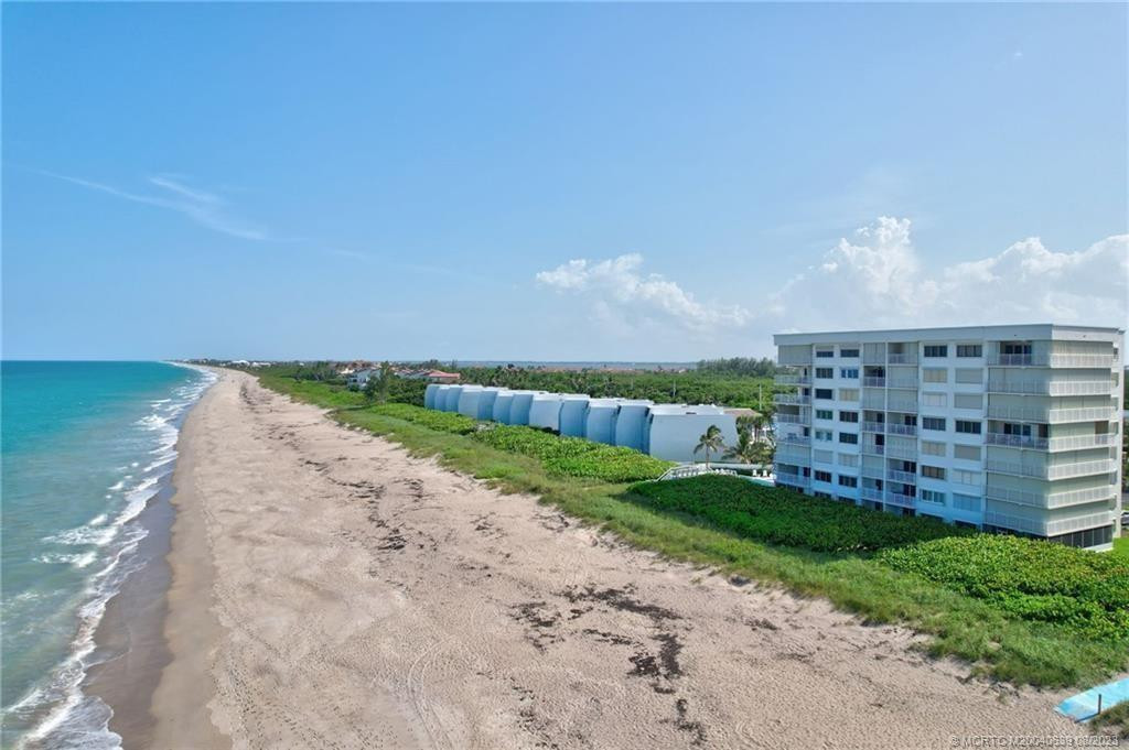 Enjoy living on the beach & Ocean from this beautifully renovated corner Condo with over 400 sq ft of screened in “L” - shaped patio. Private door leads to beach, grassed in area and pool deck.  3 sets of storm rated sliders w/shutters. Kitchen has open & spacious countertops, cabinets & pantries. Stainless steel appliances. Custom lighting. Marble floors. The primary bedroom suite with walk in closet, updated bathroom and walk-in shower.  Guest bedroom features a pull-down guest bed that doubles as an elegantly lit shelving unit. Large walk-in laundry area washer/dryer. Heated Pool, beach access, car rinse area. Close to area restaurants, shopping. Pet friendly. Fully furnished & turnkey. Milestone work completed. Healthy Reserves. Rented thru 8/1/26. Prorated income goes to new owners.