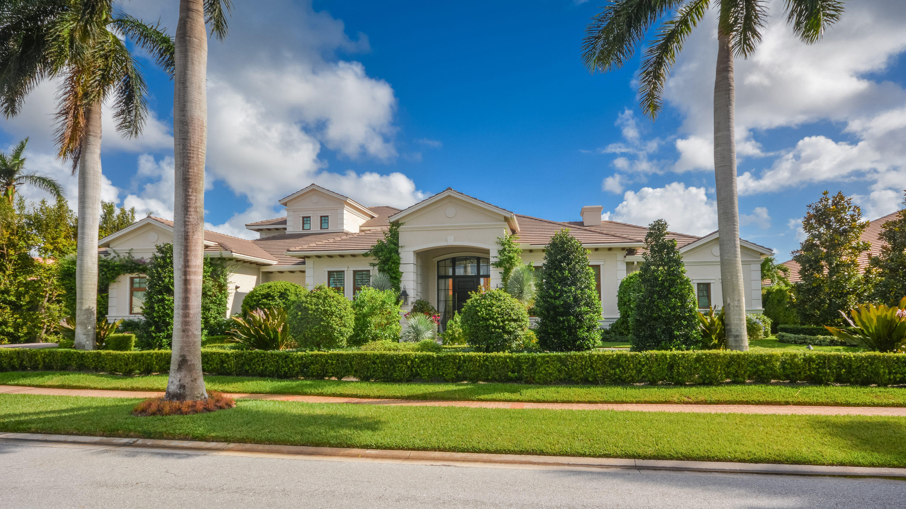This stunning, transitional estate creates a luxurious resort-like dream on an oversized half acre lot with golf course views as a backdrop to the spectacular outdoor entertainment space on a tumbled marble terrace featuring a glass-tiled waterfall pool with LED night lighting. Featuring 5 en suite bedrooms, 6 ½ bathrooms, office and upstairs family room, this estate is designed with casual elegance that gives the signature look of this meticulous design. Statuesque palms and flowering foliage make a beautiful impression at the entrance into the grand two-story foyer, where the view sweeps through the airy open living spaces in a layout that meets every need for today's discriminating buyer. The great room's large open gathering space centers around a showpiece kitchen designed for the casual family or master chef with furniture-style cabinetry, semiprecious quartz counters, and an island/bar below glass cylinder pendant lighting. High-end appliances include a "Live" European six-burner gas range and double ovens, two dishwashers, two beverage refrigerators, Miele Coffee machine and side by side refrigerator/freezer and an additional built in wall oven and microwave. This designer kitchen also features a Butler's pantry that passes through to the large dining room with seating up to 14 people and a large Costco pantry.  The great room with its wall of sliding glass doors opens to a covered loggia with built-in summer kitchen and automatic retractable screens and overlooks the sweeping golf course view and resort style pool/patio. The luxurious Primary Suite has a view of the pool and contains two huge custom walk-in closets, one a boutique-style wardrobe room with glass-topped island table, and separate "His and Hers" sumptuous baths, both featuring glass-enclosed multi-head showers and top of the line Toto private water closets. The adjacent wood paneled main office overlooks the front tropical landscape. The private second level contains 3 large en suite bedrooms, family area and additional laundry room.

The resort style patio with oversized linear pool, raised spa and 3 cascading water features is perfect for warm South Florida days with the iridescent glass tiles shimmering in the sun light. 

This picture-perfect designer-finished estate creates a luxurious showplace for South Florida's indoor/outdoor lifestyle at its finest and is complete with Smart-house technology including a Control 4 system. Other features include full house generator, impact resistant windows and doors, side load 3 car garage with room for car lifts and a grand circular driveway/motor court.