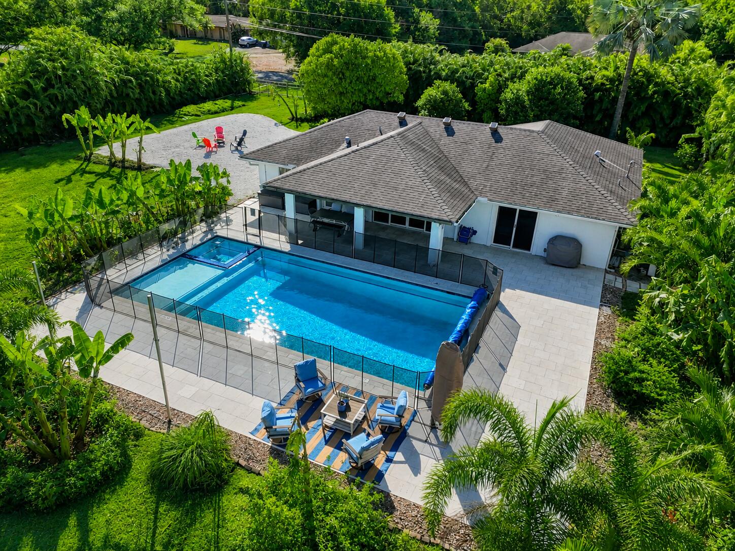 Beautifully updated CBS home on 1.15 fully fenced acres in Jupiter Farms with a gated entrance and separate access for a boat or RV. This spacious 4-bedroom, 3-bath residence features vaulted ceilings, impact windows, oversized porcelain wood-look tile flooring, multiple mini-split systems, and a renovated kitchen with quartz countertops and stainless steel appliances. The flexible floor plan includes two primary suites with en-suite bathrooms and a cabana bath with direct pool access.  Enjoy true Florida living with an oversized heated smart pool featuring a spa and sun shelf, expansive patio space, fire pit, and mature fruit trees. Additional highlights include an air-conditioned detached garage, storage shed, in-home laundry, and large sliders overlooking the private backyard oasis.