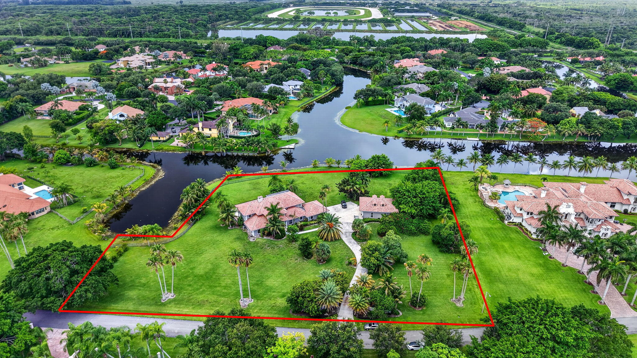 Spectacular cul-de-sac estate on 2.76 acres, offering expansive long lake views within a prestigious 24-hour manned gated community. This exceptional residence showcases elegant marble and hardwood flooring, granite countertops, crown molding, and many additional upscale details. The luxurious primary suite features a dramatic 40-foot balcony overlooking the pool and breathtaking lake views. A separate approximately 1,800-square-foot guesthouse offers three bedrooms and two baths, providing spacious accommodations and serene privacy for guests or extended family. This remarkable property offers ample room to create a private tennis court or additional outdoor amenities.