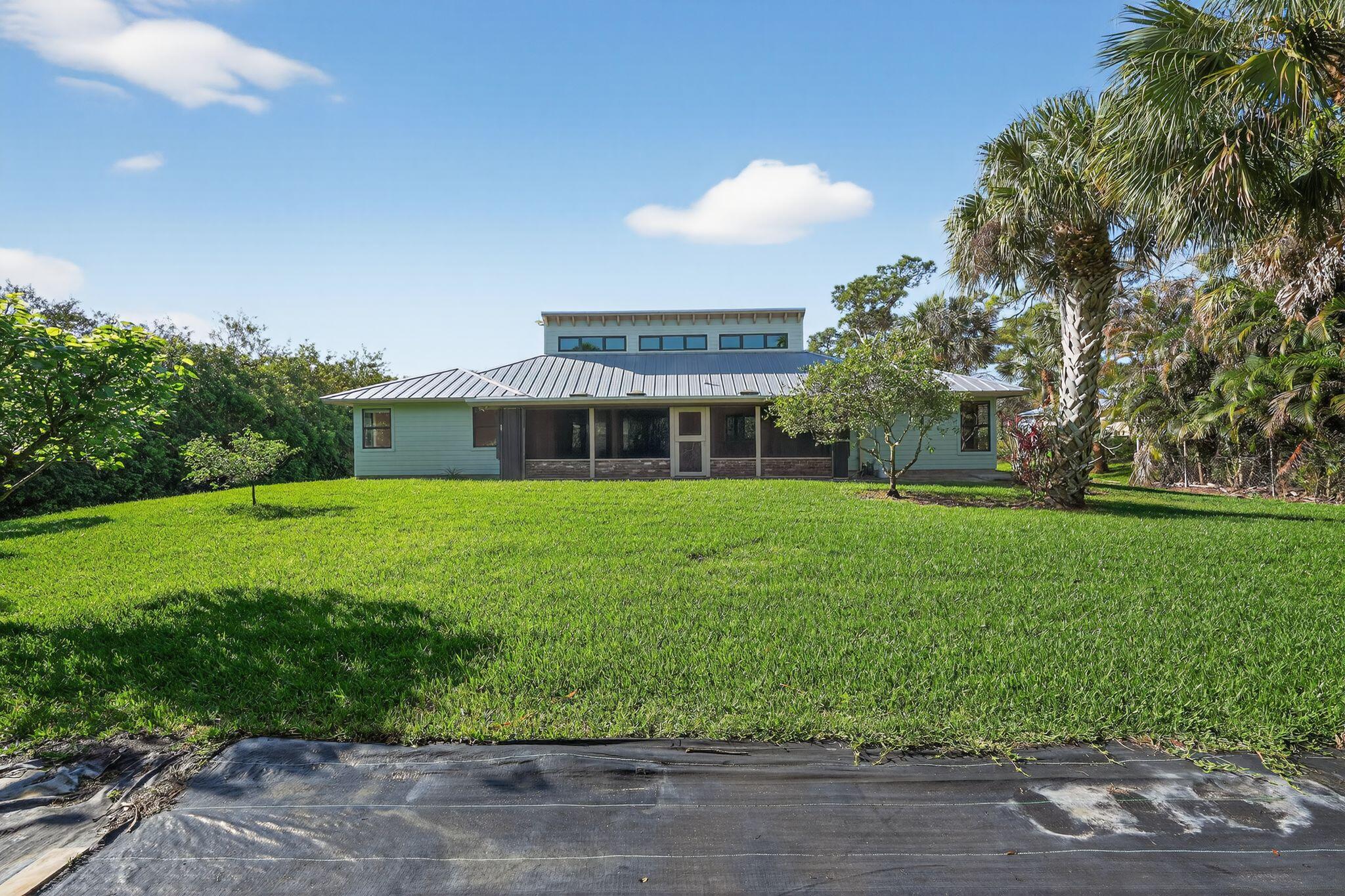 Coastal Living Meets Florida Charm - Hobe Sound Gem on Half an Acre Welcome to 8535 SE May Terrace, a beautifully maintained 4-bedroom, 2-bath single-family home that combines comfort, privacy, and convenience in one of Hobe Sound's most desirable neighborhoods. Situated on a 1/2-acre lot at the end of a peaceful dead-end street, this 3,000 sq. ft. residence blends timeless Florida character with modern updates and serene surroundings. Step inside to discover vaulted ceilings lined with cedar tongue-and-groove and accented by cypress beams, creating a warm, cabin-like feel throughout the living spaces. Natural light fills the home through upgraded hurricane-impact windows.  The generous kitchen features granite countertops, stainless-steel appliances, and hardwood oak cabinetry with special hidden features. Key Property Highlights: Eco-Friendly & Efficient: Outfitted with solar panels that keep electric bills between $30-$35 per month. Features a 50-amp EV charger in the garage and a 30-amp RV hookup out front. Recent Mechanical Upgrades: Brand new AC system (unit, air handler, and compressor) installed within the last 12 months, featuring a Remy Halo air purification system. The flat roof section has also been completely redone. Master Suite Sanctuary: A custom-designed retreat featuring a one-piece solid stone sink, brushed nickel fixtures, and a seamless glass shower with dual rain shower heads, custom tile, and River Rock flooring. Tropical Backyard Oasis: Lush, professional landscaping featuring a variety of fruit trees (Mango, Papaya, Avocado, Peach, Navel Orange, Tangelo, Lime, and Mulberry) maintained by an automatic sprinkler system. Pool Ready: The expansive backyard is perfectly suited for a pool or jacuzzi, already pre-wired with the proper amperage for easy installation. Ample Storage: Large front carport designed to accommodate an RV or boat. Premium Finishes: Central vacuum system throughout, custom marble flooring/counters in the guest bath, and a large screened-in porch with brick accents and skylights. The Hobe Sound Lifestyle Experience the peace and tranquility of a true family-oriented community. You are just 2 miles from Hobe Sound Beach—widely considered one of the most beautiful, canopy-lined beaches in the area—and a short walk to the natural beauty of Jonathan Dickinson State Park. This home offers the perfect balance of secluded "Old Florida" charm and modern, high-tech convenience.