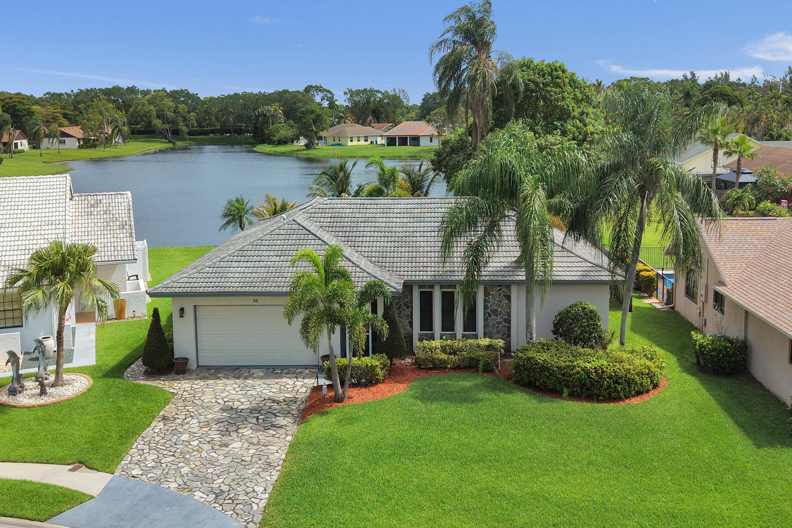 Welcome to Boynton Beach's Lakefront single-story Pool Home in the Dos Lagos community. Offering 1,886 air conditioned living square feet. This single-story residence features 3 bedrooms, 3 full bathrooms, and a spacious 2-car garage. Designed for both comfort and privacy, the split-bedroom floor plan includes a primary suite with French doors opening directly to the screened patio and pool area. A second bedroom also features its own en-suite bath, making it ideal for guests or multigenerational living. The third bedroom is conveniently located near another full bath, while the cabana bath provides direct access from the pool area—perfect for entertaining and avoiding wet footprints throughout the home.  This home offers two more sets of French doors opening to the screened patio, where you'll enjoy breathtaking views of the sparkling pool, tranquil lake, and mature mango tree. The fenced pool area creates a private backyard retreat, ideal for relaxing or hosting a gathering.  As you arrive, you'll also appreciate the beautiful natural stone driveway, welcoming screened front porch & stone coated steel metal roof. Additional upgrades include newly renovated kitchen, AC 2023, remodeled primary shower, bedrooms & primary bath have newly tiled floors, permanent wind-resistant security screens on the windows and a separate air-conditioned laundry room complete with a utility sink for added convenience. The Roof was installed in 2002. It is a type of metal roof called "Stone Coated Steel". You will also enjoy the benefits of lake-fed irrigation, helping reduce water costs while maintaining lush landscaping. With low HOA fees, Dos Lagos and Shoreline Homes residents enjoy basic cable, Wi-Fi, and virtual gate access. Conveniently located near shopping, dining, major highways, the Brewery, airports, and everything Boynton Beach has to offer. This home combines value, location, and lifestyle. Priced to allow for your personal updates and finishing touches, this lakefront pool home presents an exceptional opportunity to own your own slice of paradise in the heart of Boynton Beach. Schedule your private showing today and experience the beauty, privacy, and potential this exceptional property has to offer.   Cash offers must be accompanied by POF, financed offers must be accompanied by DU Pre-Approval. All information contained in this listing is meant to be accurate, but is subject to errors and omissions. All sizes/Info approximate. FARBAR AS-IS contracts.