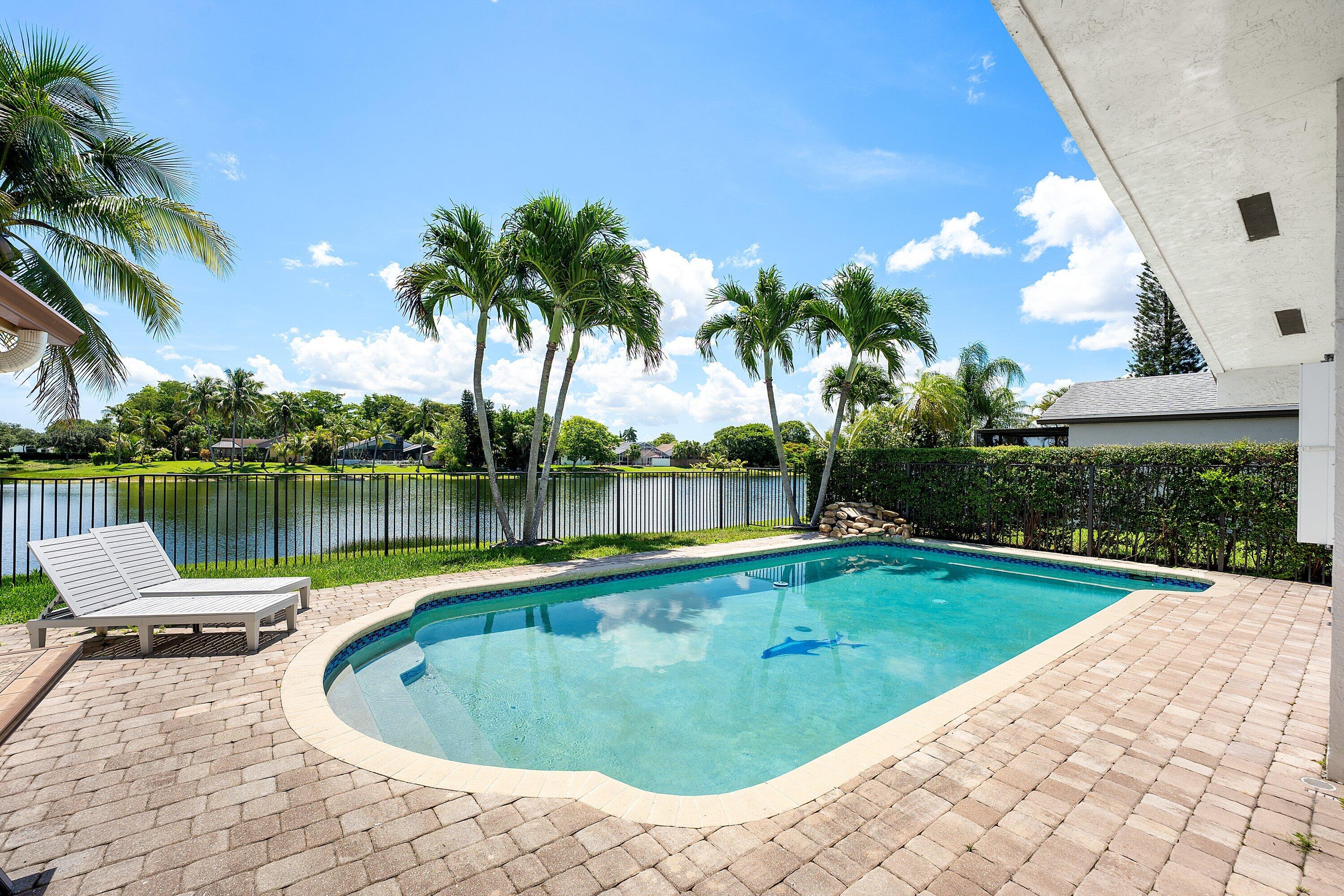 Welcome to Country Landing, a picturesque enclave within the highly sought-after Logger's Run community in West Boca Raton. Perfectly positioned on a nearly 7,500-square-foot lakefront lot, this beautifully maintained 4-bedroom, 2-bath pool home offers 1,874 living square feet (2,612 total) and enjoys one of the community's most private streetscapes. Highlights include a highly desirable split-bedroom floor plan, soaring vaulted ceilings, abundant natural light, tranquil long lake views, an oversized primary suite with an impressive walk-in closet and private cabana bath, indoor laundry room, oversized two-car garage, 2021 A/C, complete accordion shutters, and an oversized side yard with the potential to expand the fenced yard. Designed for everyday living and effortless entertaining, the spacious interior flows seamlessly to a private backyard retreat featuring a sparkling pool, expansive pool deck, and tranquil long lake views. Three additional bedrooms provide flexibility for guests, or a home office, while the thoughtfully designed layout offers exceptional everyday functionality.  Additional features include complete hurricane protection with accordion shutters throughout, a 2021 air conditioning system, and an oversized side yard thanks to a community easement, offering the potential to expand the fenced yard and create even more outdoor living space.  Residents of Country Landing enjoy an exceptionally low HOA of just $350 per quarter while benefiting from everything Logger's Run has to offer, including miles of scenic walking and biking trails, playgrounds, basketball and tennis courts, athletic fields, and beautiful neighborhood parks. Unlike many Boca Raton communities, Country Landing offers exceptional flexibility with no rental, pet, or commercial vehicle restrictions, allowing owners to keep boats and RVs at home. Conveniently located near shopping, restaurants, grocery stores, top-rated public and private schools, and within walking distance of multiple places of worship, this home offers an exceptional combination of privacy, flexibility, and convenience.