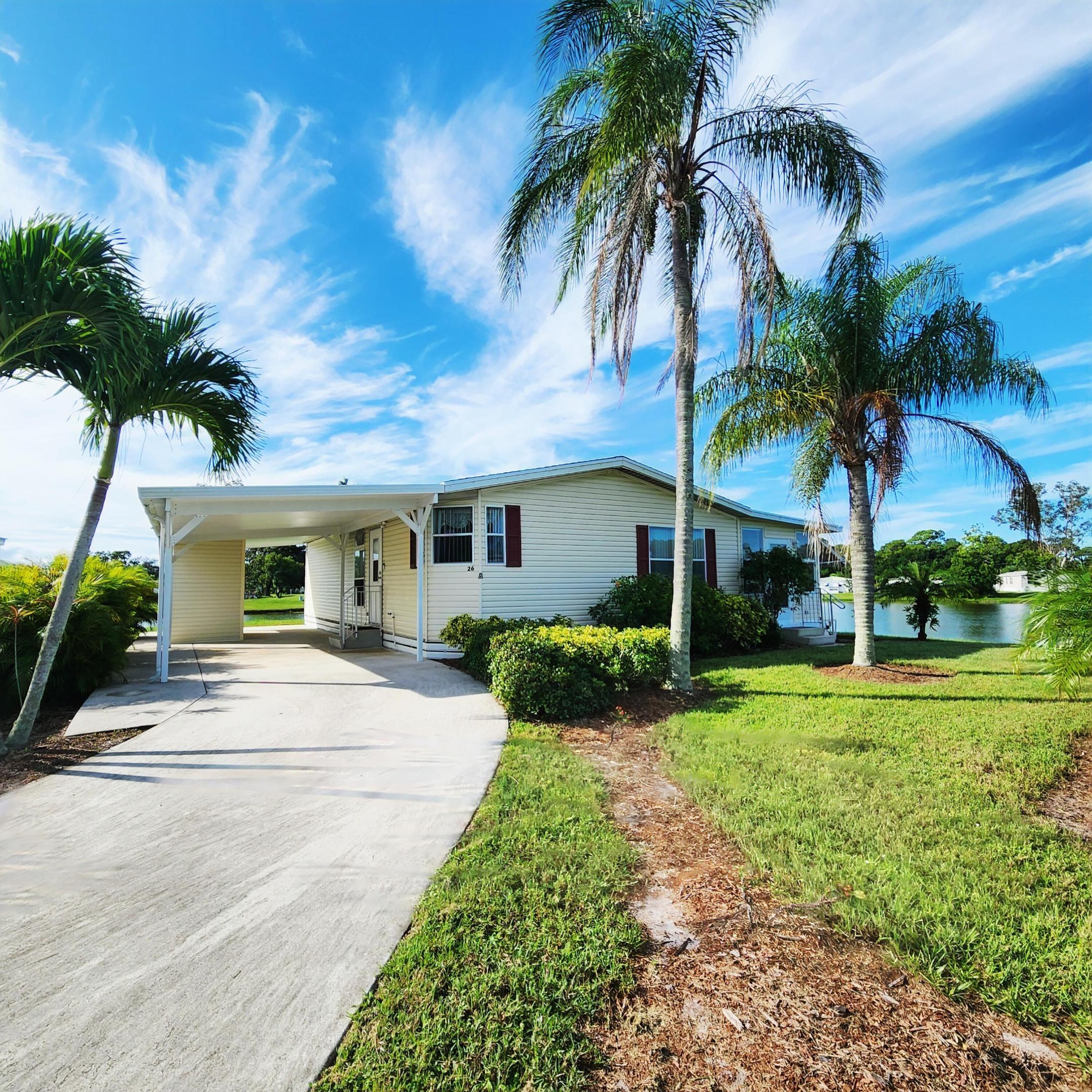 Natural beauty surrounds this 2bed/2bath home, nestled in the back of a CulDeSac on a large corner lot w/ panoramic lake views.Watch ducks & wildlife glide across water & colorful evening sunsets in large window/screened in Florida Rm. Expansive lot offers privacy & space, great for pets, gardening, grilling, entertaining, or soaking in peaceful surroundings. Recent updates include a 2020 roof, 2023 AC & 2022 carpet/flooring, WaterHtr 2020. PRIME LOCATION; near beach, grocery stores, post office, banks, hospitals, pharmacy & more! Lot rent of 1080.98 includes private golf course (no fees to play) heated pool, fitness, pickleball, tennis, shuffleboard, bocce, gym, library, card games, MahJong, Bible study, wood workshop, parades, dinners, dances, trips & more! Lawn cutting & trash included