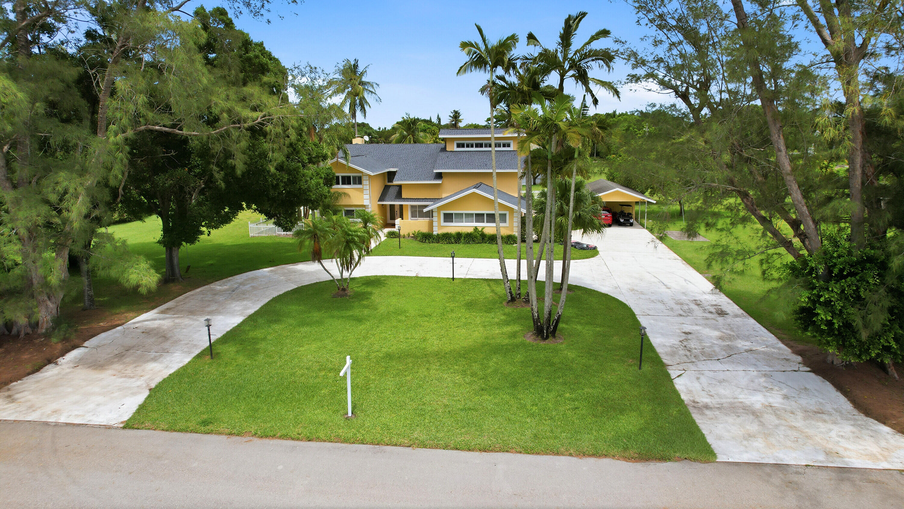 Is there a 4-bedroom home in Palm Beach County with acreage, privacy, a pool, and water views? This exceptional estate home in Tara Estates offers a rare opportunity to own 1.22 acres in one of the most desirable communities in Boynton Beach. Nestled on a sprawling 53,143-square-foot lot, this two-story CBS home features 4 bedrooms, 3 bathrooms, impact windows, and breathtaking panoramic lake views from nearly every room. Surrounded by mature trees and lush landscaping, the property provides the privacy and outdoor space that many South Florida buyers are searching for. Inside, you'll find soaring volume ceilings, a dramatic floor-to-ceiling window, a stunning two-story wood-burning fireplace with a stone accent wall, and an elegant wood staircase that creates a grand first impression. The brand new kitchen is designed for both everyday living and entertaining, featuring granite countertops, stainless steel appliances, a wine cooler, built-in desk, and an open breakfast bar overlooking the family room. The spacious primary suite offers a private loft, ideal for a reading nook, fitness space, or home office, along with a balcony overlooking the lake. A second-floor loft provides additional flexible living space and can easily be used as a den, game room, office, or media room. Step outside to your private backyard retreat featuring a large swimming pool, expansive paved pool deck, tropical landscaping, fenced yard, and incredible water views. The generous circular driveway provides ample parking for family and guests, while a covered carport and storage shed add convenience. Homeowners in Tara Estates enjoy a remarkably low HOA fee of only $800 per year while benefiting from large estate-sized lots and a peaceful West Boynton Beach location close to shopping, dining, schools, major highways, and South Florida beaches.  Roof is brand new!  Primary ensuite and kitchen luxuriously remodeled! Rare to find such a generous oversized lot 1.22 and with luxurious modern interior finishes!