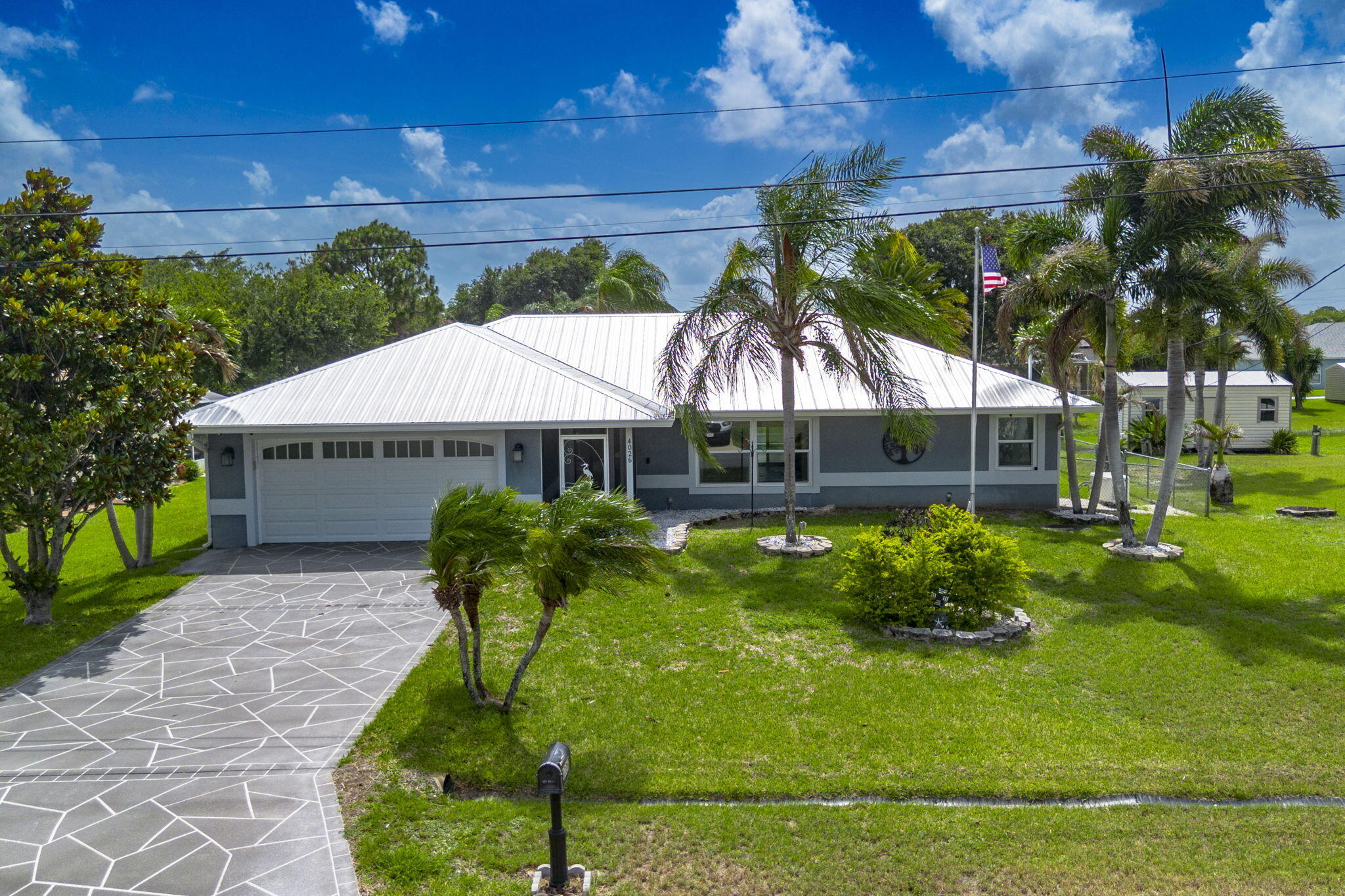 Discover the perfect combination of space, comfort, and Florida outdoor living in this beautifully maintained CBS pool home situated on an oversized .46-acre DOUBLE LOT with no HOA. Built in 2009 and offering 2,126 square feet of living space, this 3-bedroom, 2-bath home with a spacious 2-car garage provides room to spread out both inside and out. Step inside to find an inviting open-concept floor plan filled with natural light from large windows and three sets of sliding glass doors. Vaulted ceilings and rich hardwood floors enhance the home's spacious feel, while the formal dining room offers the perfect setting for gatherings and entertaining. The well-designed kitchen is the heart of the home, featuring granite countertops, a breakfast bar, pantry, Lazy  Susan cabinet storage, and a convenient pass-through window to the lanai, making indoor-outdoor entertaining effortless. The split-bedroom floor plan provides privacy for owners and guests alike. The spacious primary suite features a walk-in closet and an ensuite bath complete with a relaxing walk in jet tub. Outdoor living shines with a screened and heated pool, expansive screened lanai, fenced dog run, and plenty of yard space thanks to the Double Lot. Bring all your toys! Additional features include impact windows and doors, a 2021 metal roof, 2020 air conditioning system, 2024 water heater, public water and sewer, generator, 500-gallon propane tank, two storage sheds, pull-down attic stairs, and a split A/C unit in the garage. The oversized garage offers extra cabinetry for exceptional storage and workspace. Located in a well-established Port St. Lucie neighborhood, you'll enjoy quick access to I-95, the Florida Turnpike, Becker Road, and Port St. Lucie Boulevard. Tradition, Darwin Square, shopping, dining, parks, and the beautiful Treasure Coast beaches are all just a short drive away. This exceptional property offers the rare combination of a double lot, modern updates, and resort-style outdoor living—all with the freedom of no HOA.