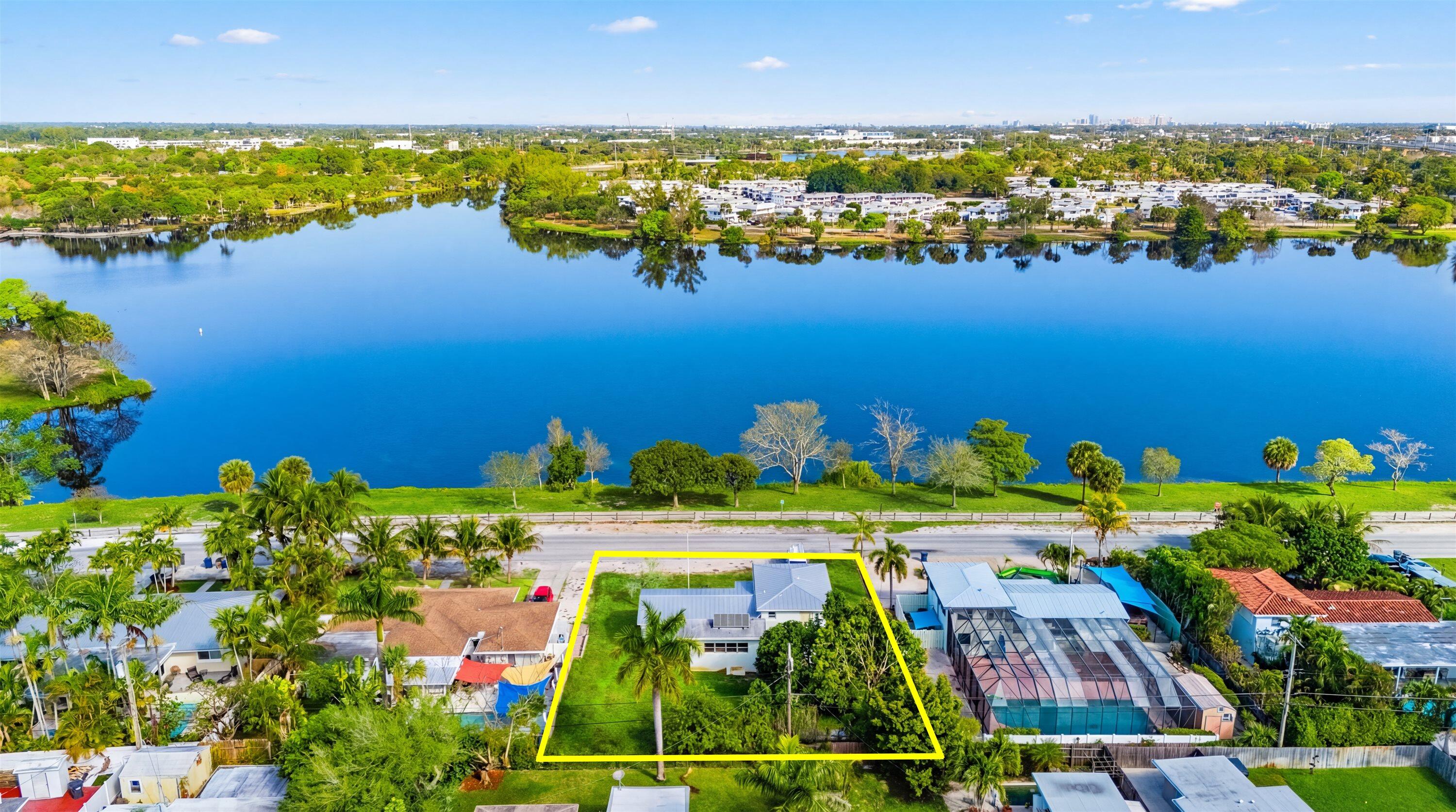 Wake up to stunning lake views every day! This beautifully updated split-level home overlooks Lake Osborne and sits on a spacious lot surrounded by mature avocado and mango trees. Featuring 3 bedrooms, 2 bathrooms, and a full basement that spans the entire footprint, this home offers both charm and versatility. The kitchen features bamboo wood cabinetry, granite countertops, and a full appliance package, while updated flooring creates a warm and inviting flow throughout. Additional highlights include a 2019 metal roof, solar water heater, rain gutters, and a 2-car garage with direct basement access. Laundry hookups are available both inside the home and in the garage. Ideally located just minutes from pristine beaches, scenic parks, and Palm Beach International Airport!