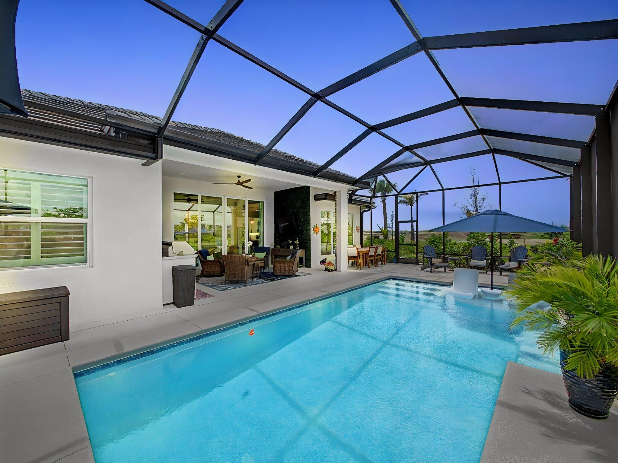 Better than new! Located within the highly desirable community of Belterra at Tradition, this exceptional 3-bedroom + den, 3-bathroom pool home showcases over $100,000 in premium builder and homeowner upgrades, delivering a level of luxury and customization rarely found in today's market. The highly sought-after Iris Grande model seamlessly combines sophisticated design, modern comfort, and resort-style outdoor living, creating an elegant yet functional residence designed for both everyday living and upscale entertaining. Inside, the home features upgraded tile flooring throughout, plantation shutters on all windows, designer chandeliers, custom drapery, upgraded ceiling fans, recessed lighting, and thoughtfully designed pocket doors that enhance the home's open and airy layout. The gourmet kitchen serves as the centerpiece of the home and is beautifully appointed with upgraded quartz countertops, an enhanced kitchen island, upgraded cabinet package with soft-close hinges, striking designer tile backsplash, decorative glass corner cabinetry with illuminated shelving, and custom pendant lighting over the oversized island. The adjacent dining area is equally refined with a custom chandelier, upgraded drapery, and transom windows that fill the space with natural light. The spacious primary suite offers a luxurious private retreat featuring custom his-and-her closets, upgraded vanity countertops, framed mirrors, and upgraded designer faucets. The versatile den/office with dual pocket doors provides the ideal flex space for a home office, media room, or guest accommodations. Additional upgrades throughout the home include electrical enhancements and a garage pre-wired for electric vehicle charging, adding both convenience and future-ready functionality.  Step outside to your own private backyard oasis where resort-style living truly comes to life. The expanded custom pool and oversized screened enclosure feature an upgraded sun shelf, elegant water features, umbrella sleeve, upgraded deck space, TV pre-wire, and a stunning decorative ivy wall that creates the perfect setting for entertaining or relaxing year-round in complete privacy. Residents of Belterra at Tradition enjoy a premier lifestyle with HOA fees that include Bluestream TV, high-speed internet, alarm monitoring, and full landscaping maintenance, allowing for effortless luxury living in one of Tradition's newest and most desirable communities.