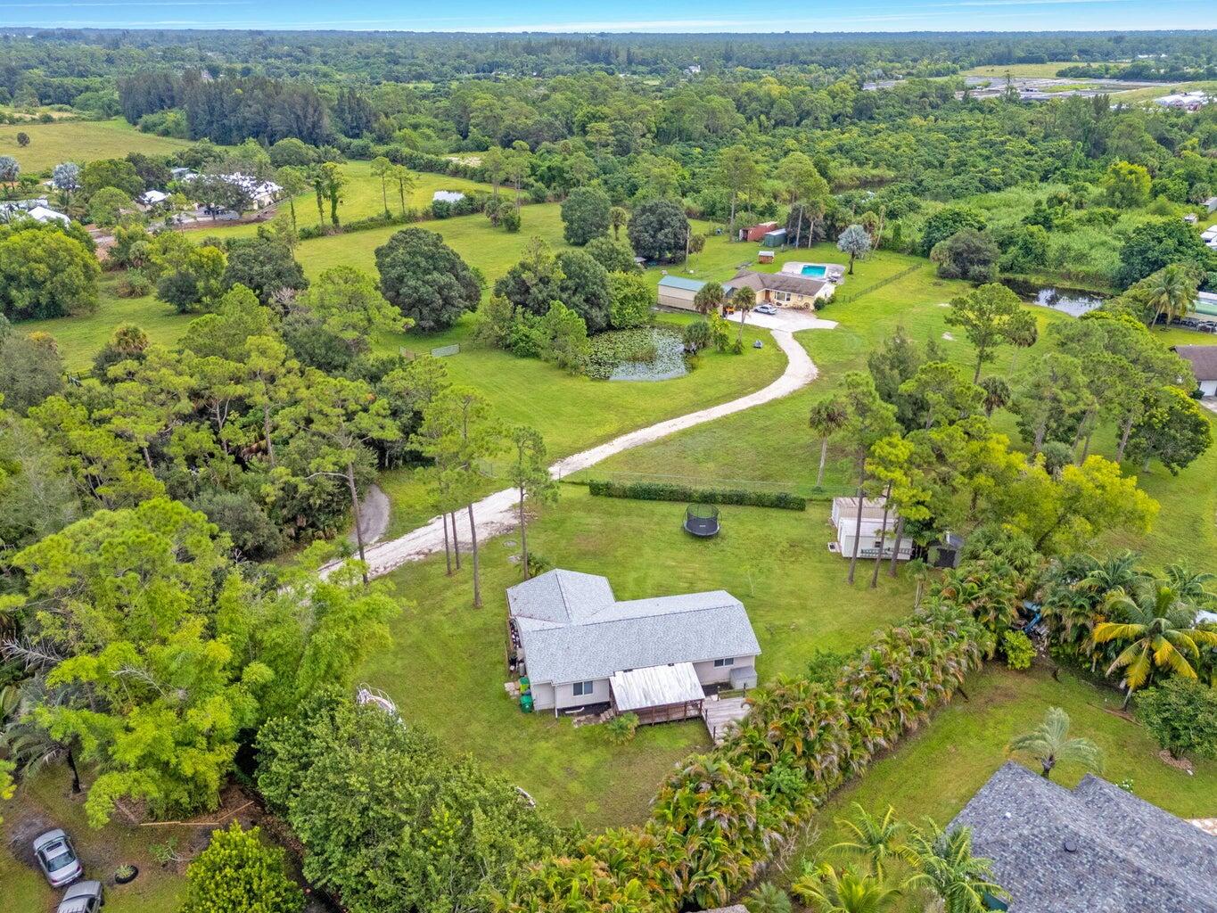 This beautifully maintained home nestled privately away from busy roads features 3 spacious bedrooms and 2 full bathrooms, all set on a large, agriculturally/residentially zoned lot with no HOA restrictions. Step inside to find gorgeous wood floors throughout, creating a warm and inviting atmosphere. The home features a NEW roof (2023), NEW impact windows, and NEW A/C system (2022) giving you peace of mind and energy efficiency for years to come. Enjoy Florida living year-round with expansive screened-in patios, ideal for relaxing or entertaining. A large workshop shed provides ample space for tools, hobbies, or storage.