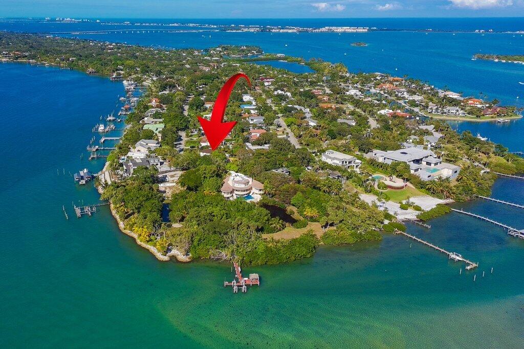 Sewall's Point latest remodel has arrived! Absolutely stunning and truly move-in ready. This exceptional residence has been completely gutted to the studs and thoughtfully reimagined from top to bottom, delivering modern luxury in one of Stuart's most coveted coastal communities. Often called one of Florida's best-kept secrets, Sewall's Point is an exclusive barrier island located just north of Palm Beach, nestled between the St. Lucie River and the Indian River Lagoon in Martin County. Voted Coastal Living's Happiest Seaside Town, the area is a nationally recognized Tree City and Audubon Society-Certified Bird Sanctuary, known for its lush canopy, protected wildlife, and timeless Old Florida charm. Situated in High Point at the island's southern tip, this property enjoys minimal traffic. The two-story, Mizner-inspired concrete block home sits on over half an acre, surrounded by all-new tropical landscaping and outdoor lighting.  Designed to live large, this 4-bedroom residence offers the rare flexibility of a primary suite on either the first or second floor. The bright, open floor plan is ideal for relaxed everyday living and effortless entertaining. The entire living area features all-new oversized porcelain wood-look tile, creating a seamless and sophisticated flow throughout.  The brand-new chef's kitchen is a true showstopper, featuring white cabinetry, Quartzite countertops, a large island with dramatic waterfall edge, stunning marble backsplash, and new Café appliances. Also, separate bar area for entertaining inside and out! Plus a brand-new laundry room adds style and function to the home. Each of the three additional bedrooms features its own en-suite bathroom, all finished with meticulous marble selections, providing privacy and luxury for family and guests alike. Upstairs, between the two bedrooms, is a versatile flex space perfect for a gym, playroom, or home office.  Upstairs has been thoughtfully reconfigured to include a luxurious primary suite with an oversized private outdoor patio. The newly remodeled spa-inspired primary bathroom features his-and-her sinks, a makeup vanity, a freestanding garden tub, and a separate marble shower an indulgent retreat.  The outdoor living spaces have been completely transformed. Enjoy all-new landscaping, updated outdoor lighting, a new tiki hut, a new pool deck, and a resurfaced pool, creating the ultimate setting for entertaining and island living. A large covered porch, screened patio, and multiple outdoor spaces further enhance the indoor-outdoor lifestyle.  Additional upgrades include all-new impact glass windows and doors throughout, reinforcing both peace of mind and energy efficiency. This home is absolutely stunning and will not disappoint. There is truly too much to list and even more to experience in person.  Schedule your private showing today and discover the best of Sewall's Point living.