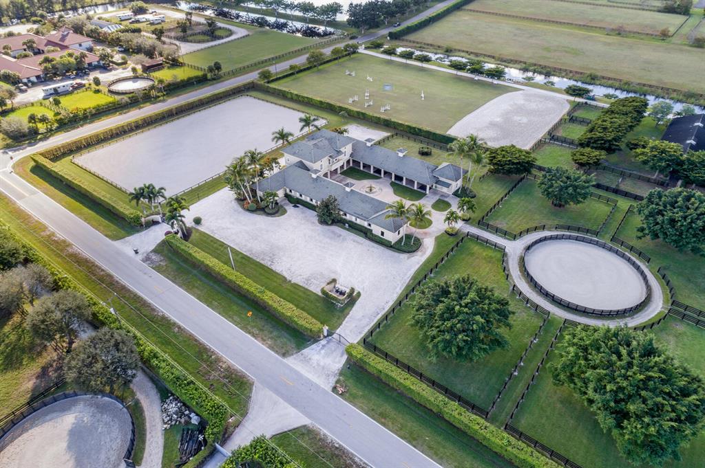 A true professional horseman's setup in Palm Beach Point East!  Designed to make the day to day more efficient and provide a calm peaceful environment for both humans and horses.  This luxurious 5 acre, 14 stall equestrian facility is located directly south of PBIEC, just over a mile hack away.  It's great location is getting even better with the new southern show expansion and access!  The farm boasts one of the largest all-weather rings in the area, with excellent drainage and top performance footing, measuring approximately 150'x230'.  The property also features 5 large paddocks, round pen, very wide aisles for aisle grooming, covered treadmill hookup, 2 full tack rooms, 1 storage room, 2 wash stalls and 3 separate apartments. The apartments include 1 studio, 1 full one bedroom apartment, and above the barn a nice 3 bed/3bath apartment with 2 balconies and large common living area.  

There are 2 large automatic gates for ease of trailer access along with an oversized parking area, established landscaping throughout the farm with a mature ficus perimeter hedge offering added privacy.  This is a relatively easy and low maintenance farm with excellent income potential.  Use the full facility yourself, or take one aisle and rent out the other.  Additional stalls are allowed. Tent stalls are permissible in this area.  City water is located one property away and could be easily brought to the property.

All new water system, heating and AC systems 2021. New irrigation, new 5 foot reinforced fencing, freshly painted main dwelling and apartments.  There is space for a walker, additional stalls, or other amenities.